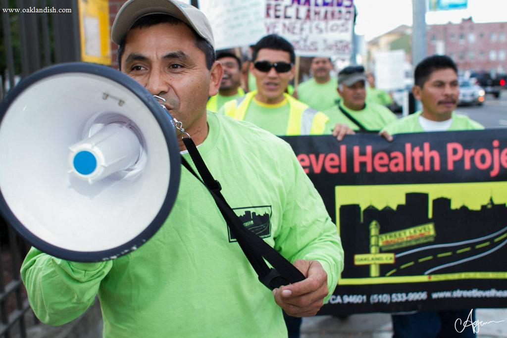man marching in street with crowd, speaking into a bulllhorn