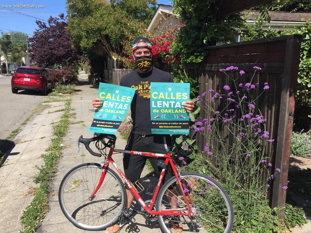 guy standing behind a bike holding signs in spanish.