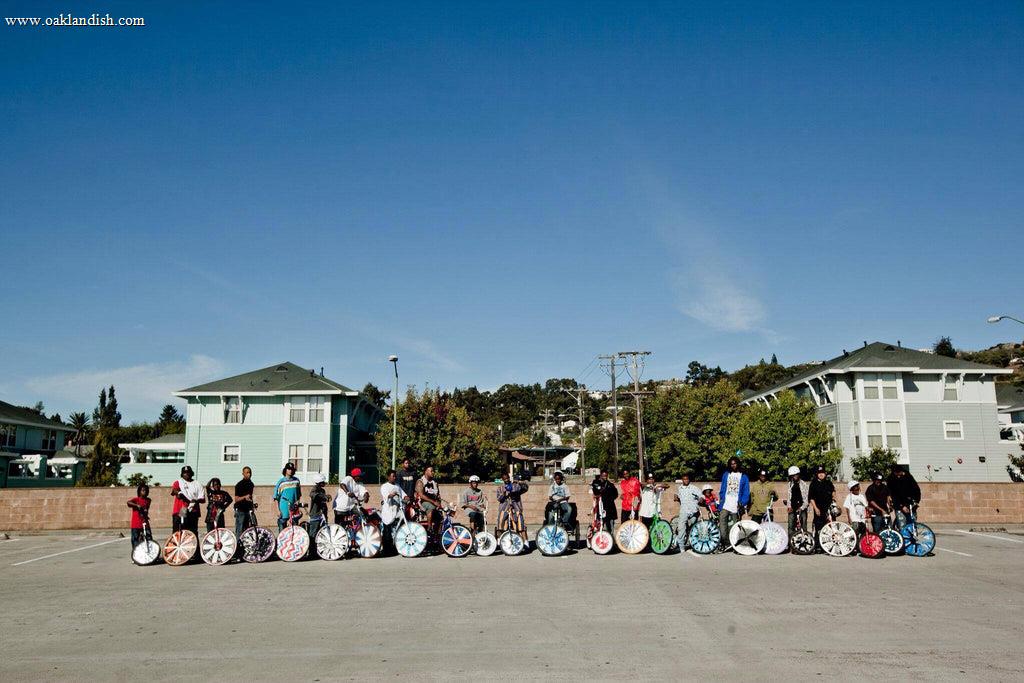 A long row of kids outside, posing with the scraper bikes they designed.
