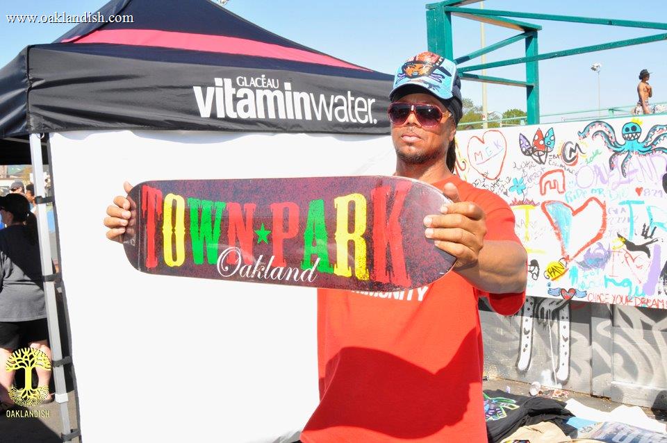 Founder of town park, k-dub, holding up a branded skate deck on site.