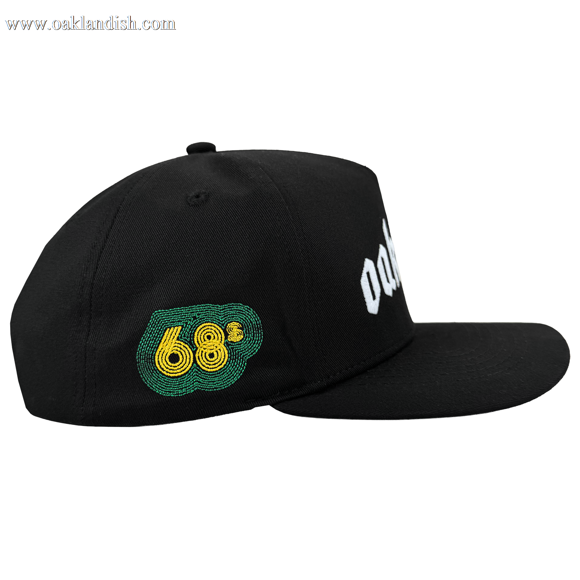The Oaklandish Oakland 68s Panel Cap is a black snapback hat with a flat brim, structured crown, green and yellow embroidered “68” on the left panel, partially visible white text on the front, shown from the side on a white background.