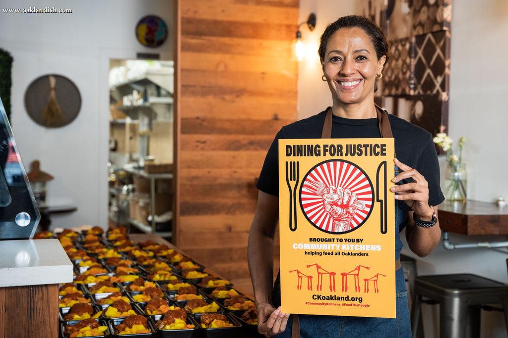 Woman holding community kitchens flyer next to a table of donated meals.