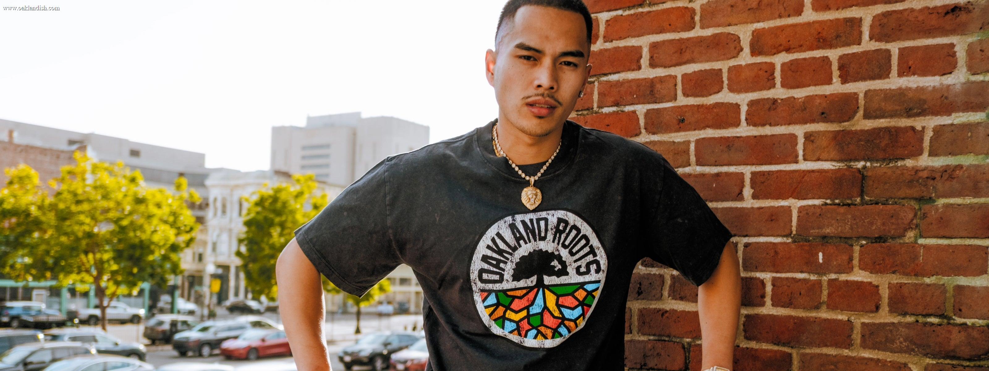 Man wearing a black tee with Oakland Roots Logo.