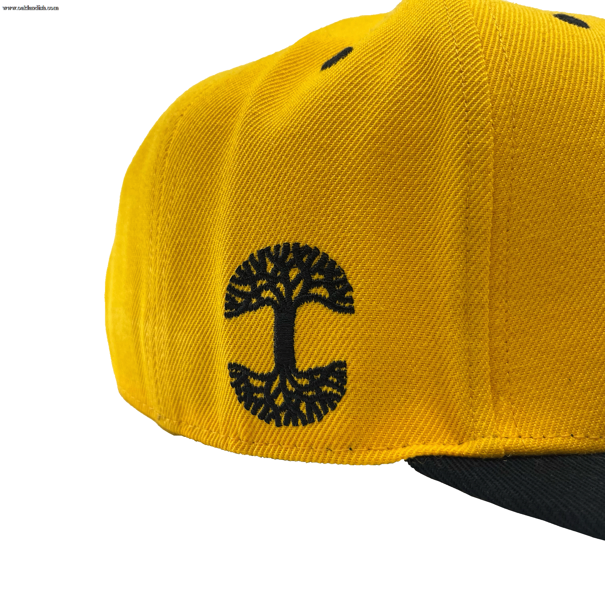 Side view of a yellow hat and black embroidered Oaklandish tree logo on the wearer's right side.