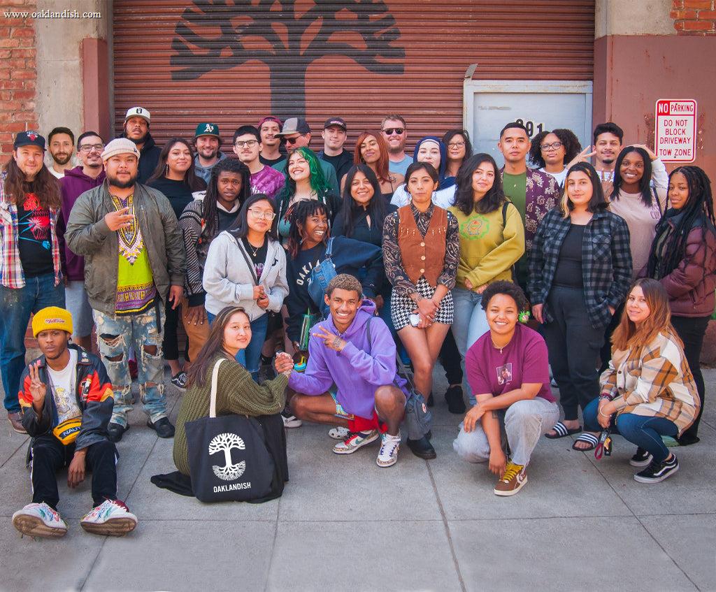 Photo of Oaklandish employees in front of building with rollup door with logo.