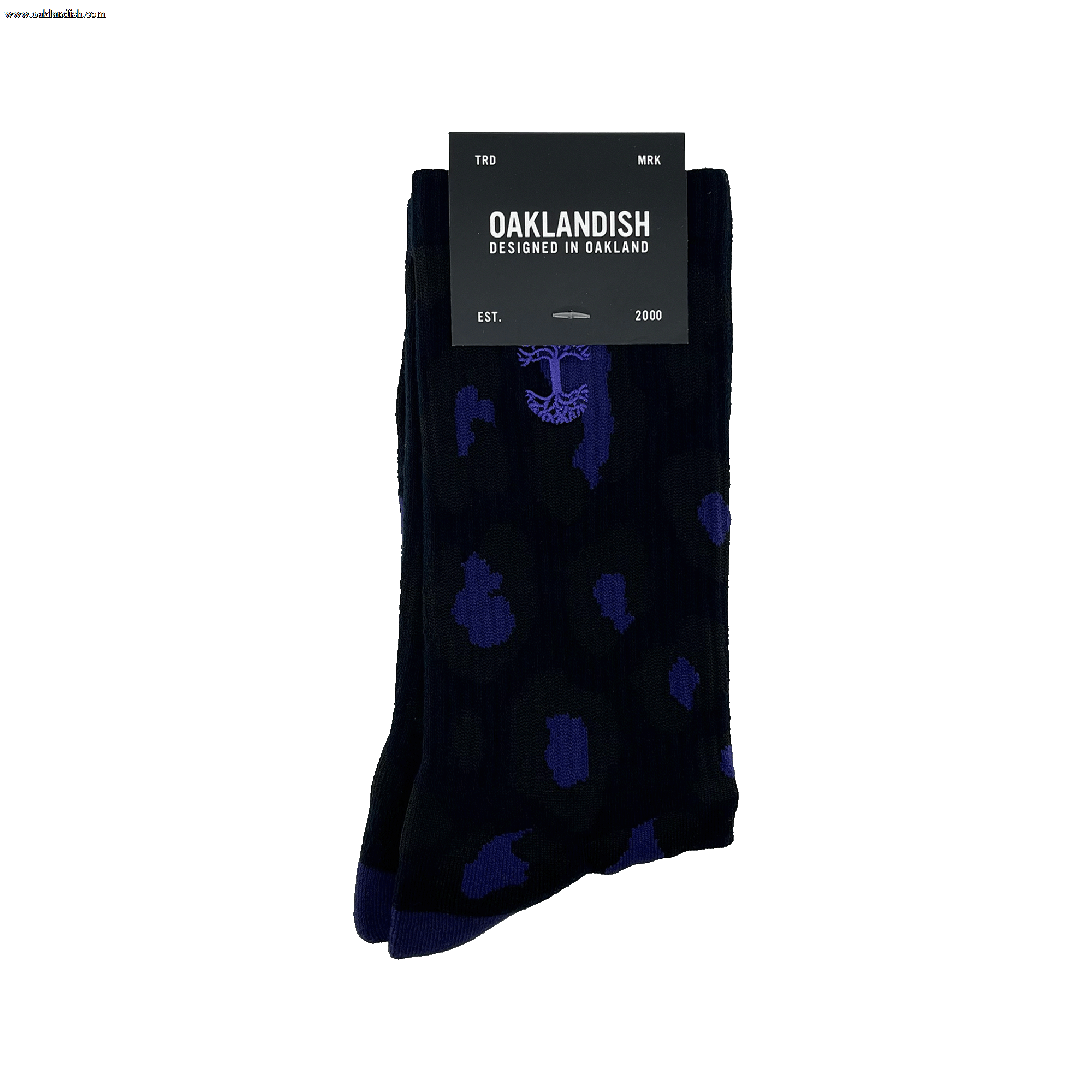 A pair of Panther Socks featuring black crew length with blue polka dot and tree designs, packaged with a black label. The label reads "OAKLANDISH" with "DESIGNED IN OAKLAND" underneath. Additional text includes "TRD MRK" at the top and "EST. 2000" at the bottom. These Oaklandish logo socks are one size fits most.