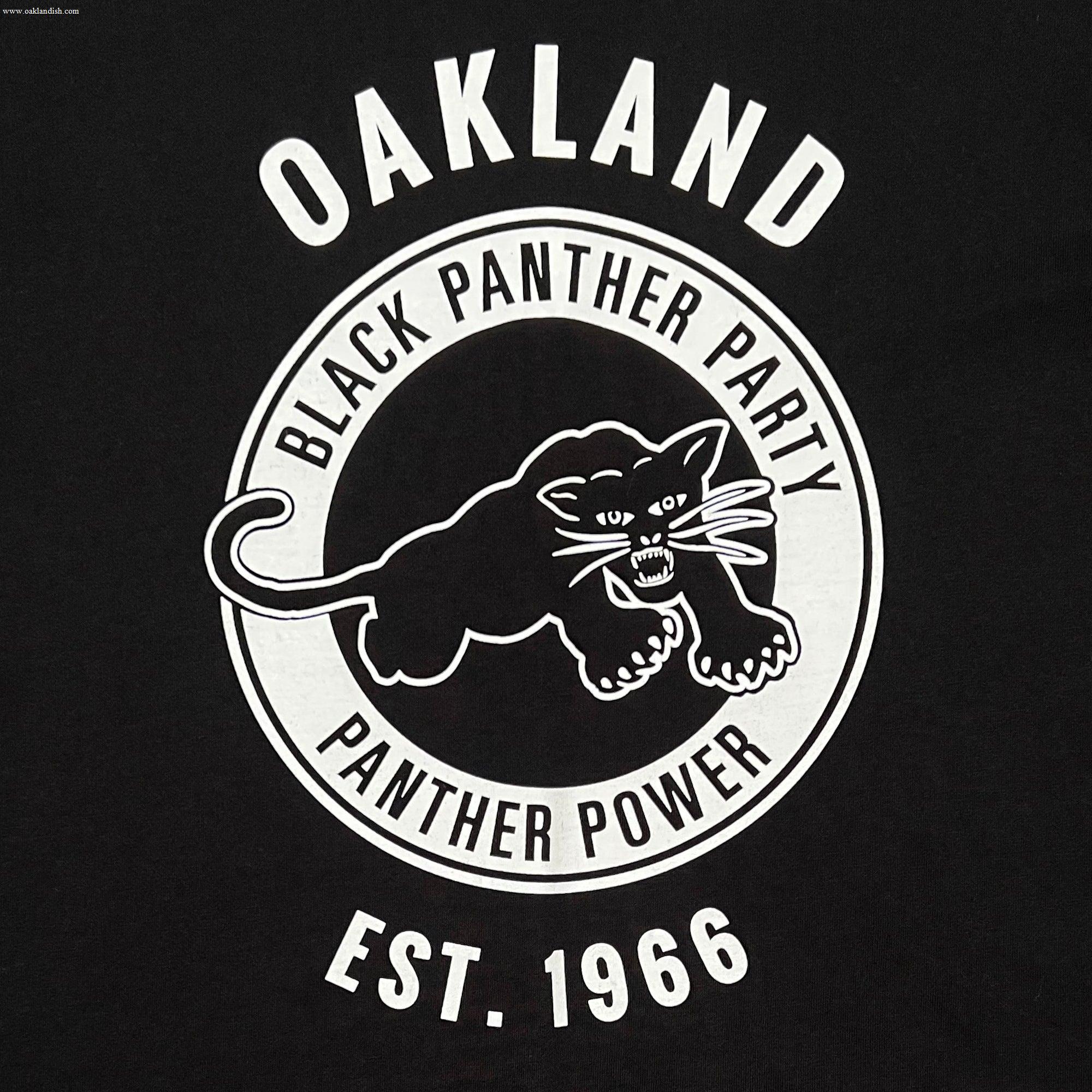 The Women's Black Panther Power Tee by Oaklandish features a circular logo with a poised black panther, accompanied by the words "Black Panther Power." The word "Oakland" is above the circle and "Est. 1966" below, all set against a striking black background with white text and imagery that pays homage to one of the era's most impactful community organizations.
