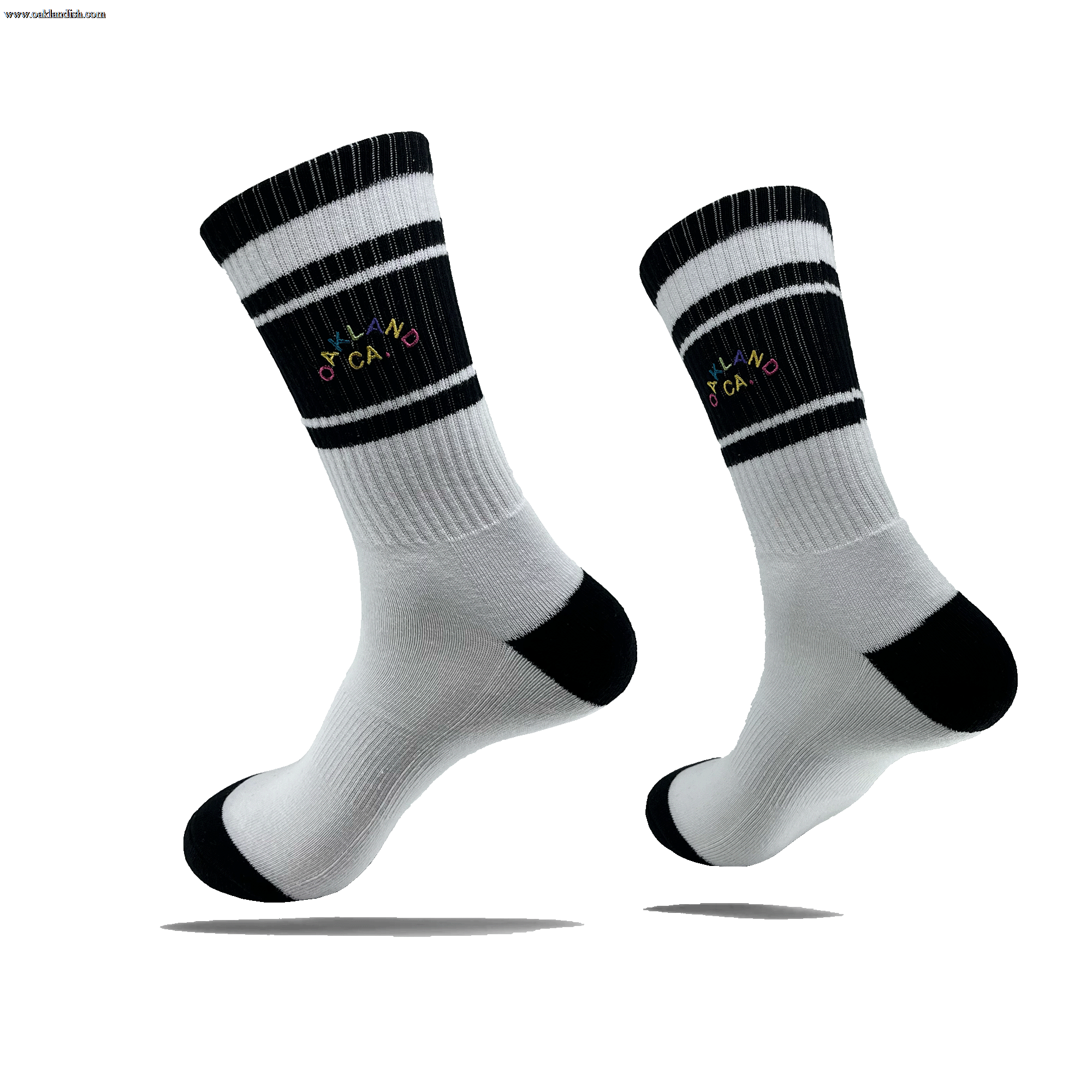 Side view of a pair of white crew socks with black stripes on the calf, black heel and toe, and full-color OAKLAND CALIFORNIA wordmark on the side calf.