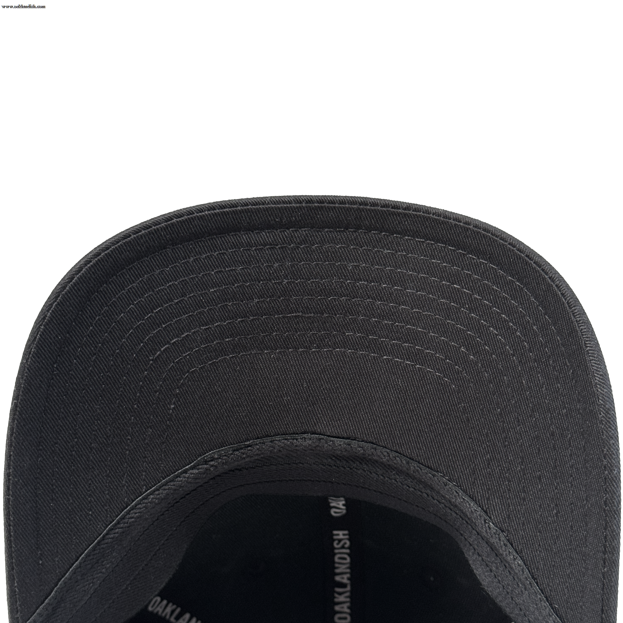 Close-up view of the underside of the Oakland Ballers Flexfit Cap, featuring a curved brim with visible concentric stitching and part of the interior, crafted from durable polyester by Oakland Ballers, with some partially visible printed text.