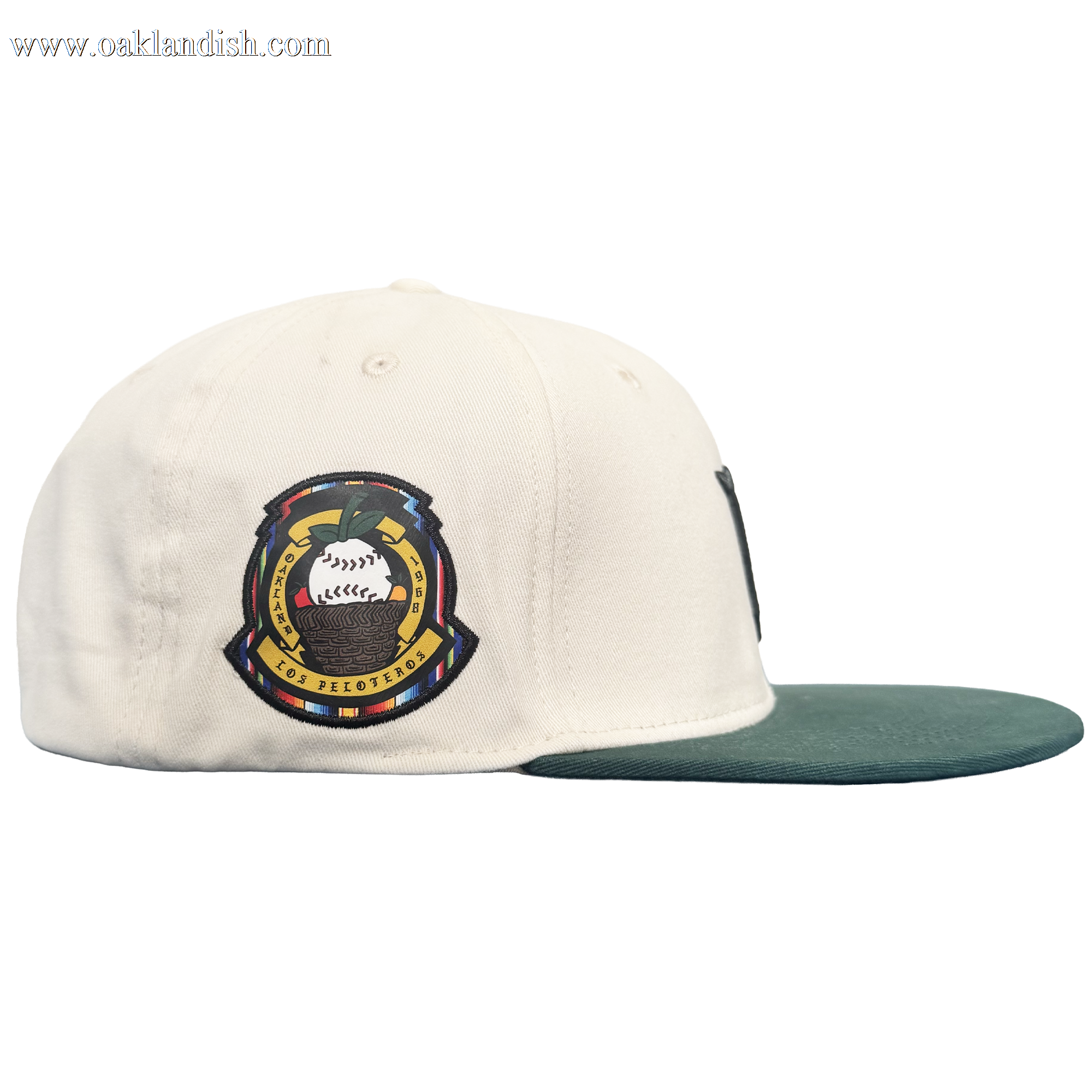 A white Oakland Peloteros Hat by the Oakland Ballers is displayed from a side view. The hat features a green brim and a colorful embroidered patch with a stylized baseball, crossed bats, and intricate detailing—a tribute to the team as an exciting addition to the Pioneer League. The plain white background emphasizes the vibrant colors and design of the cap.