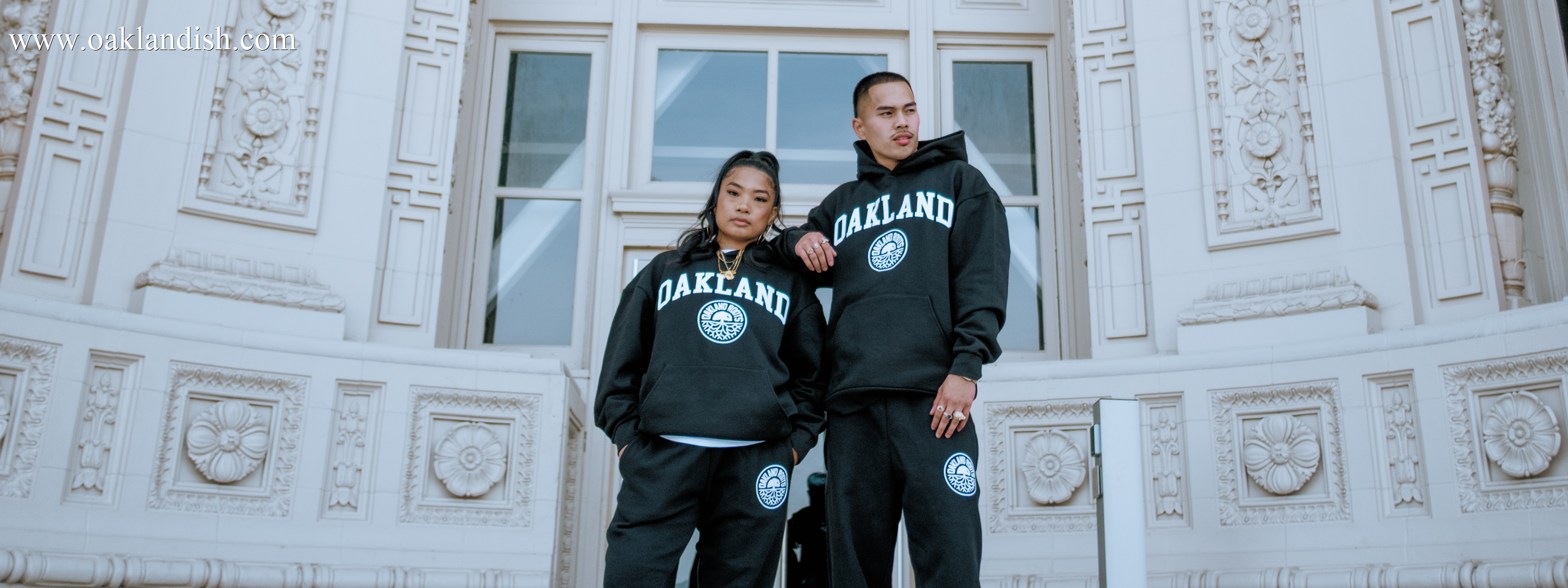 Black Oakland Roots RC joggers with elastic waist and full-color ROOTSSC wordmark on right leg lying outdoors on grass.