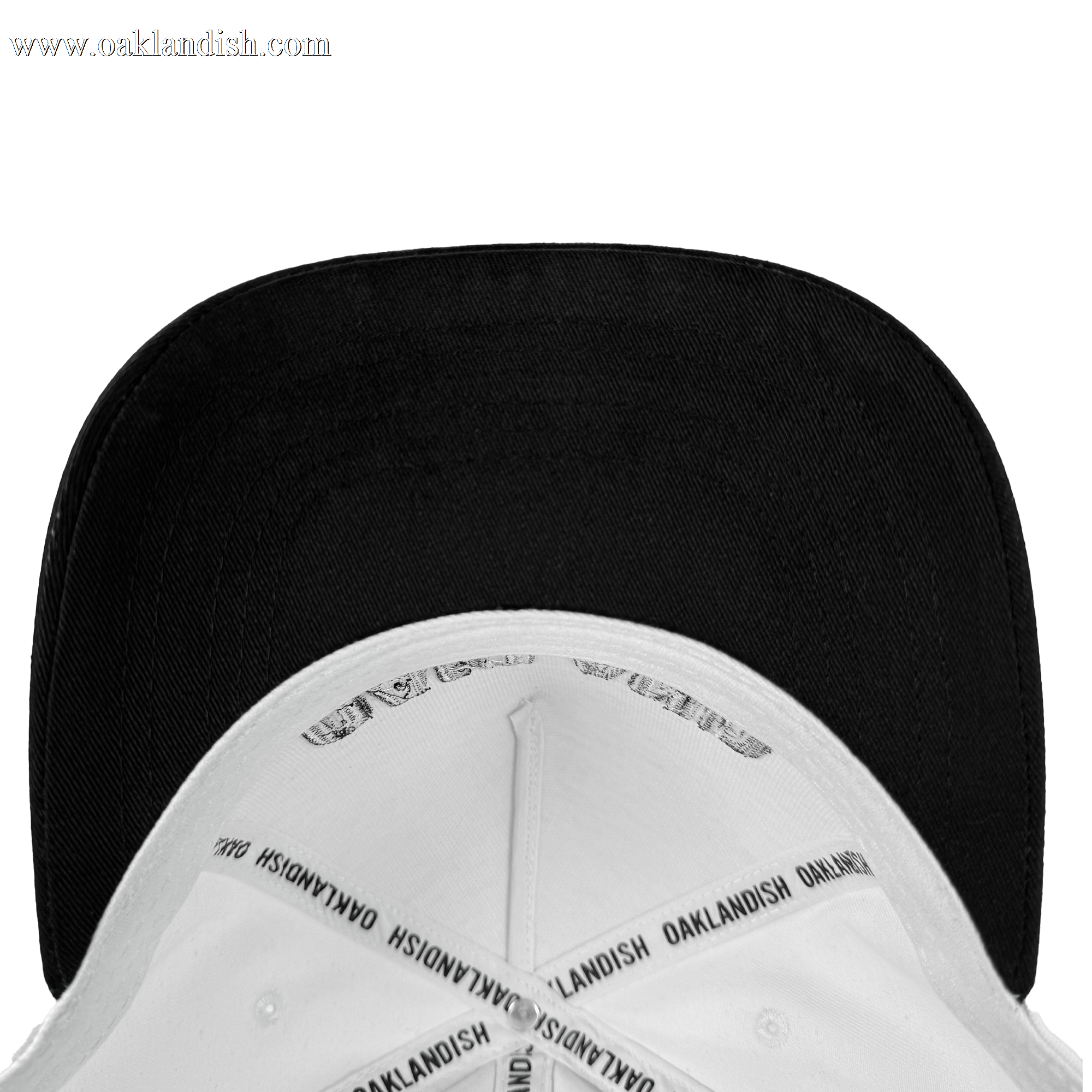 The Oakland Beisbol 5 Panel Cap by Oakland Ballers is a white snapback hat with a black underside of the brim. Inside seams have "OAKLANDISH" printed repeatedly on white tape. Shown from above on a plain white background.