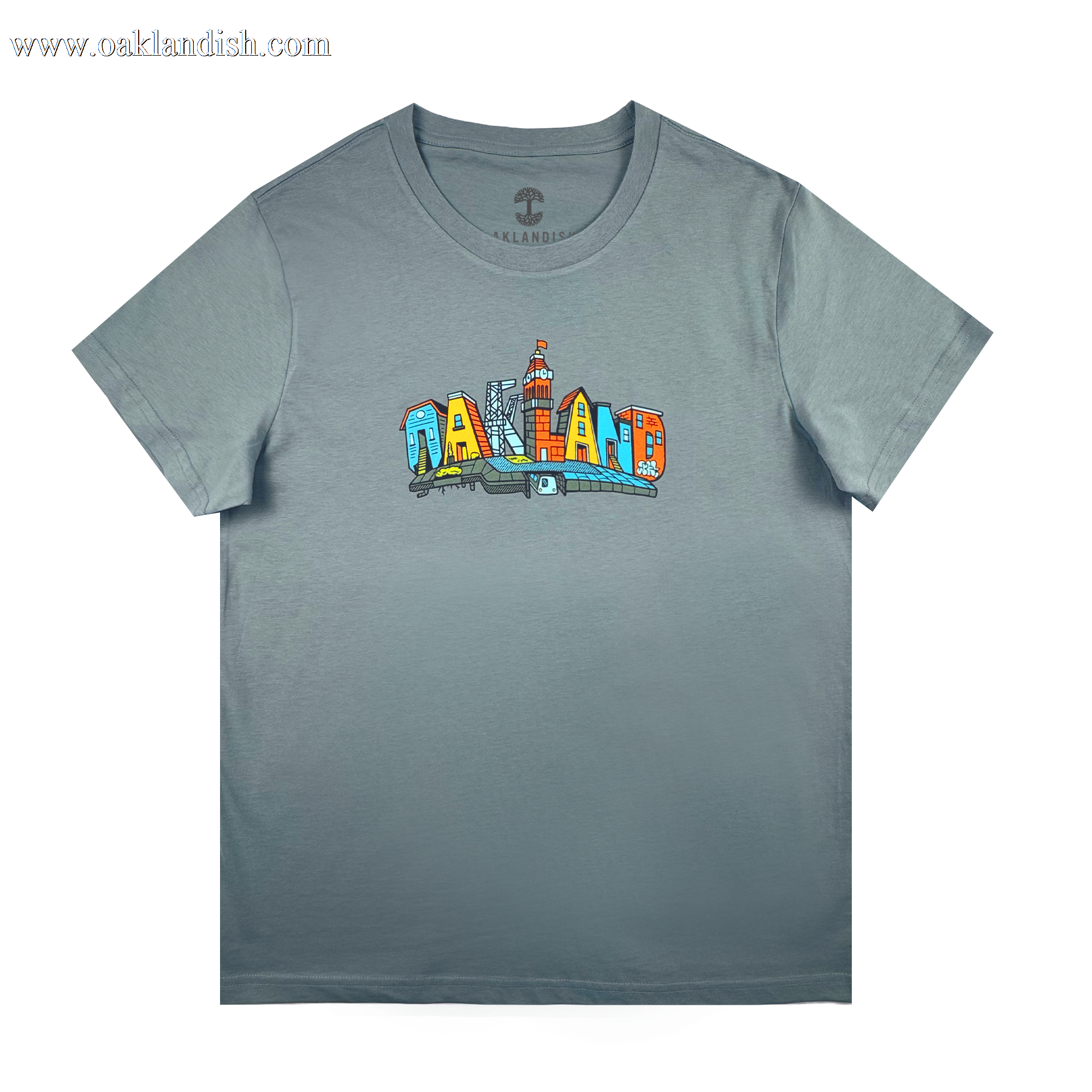 The Oaklandish Women's Blockletters Tee is a gray cotton shirt with "OAKLAND" in bold, colorful cartoon-style letters featuring city elements and skyline details, all above a subtle shadow graphic.