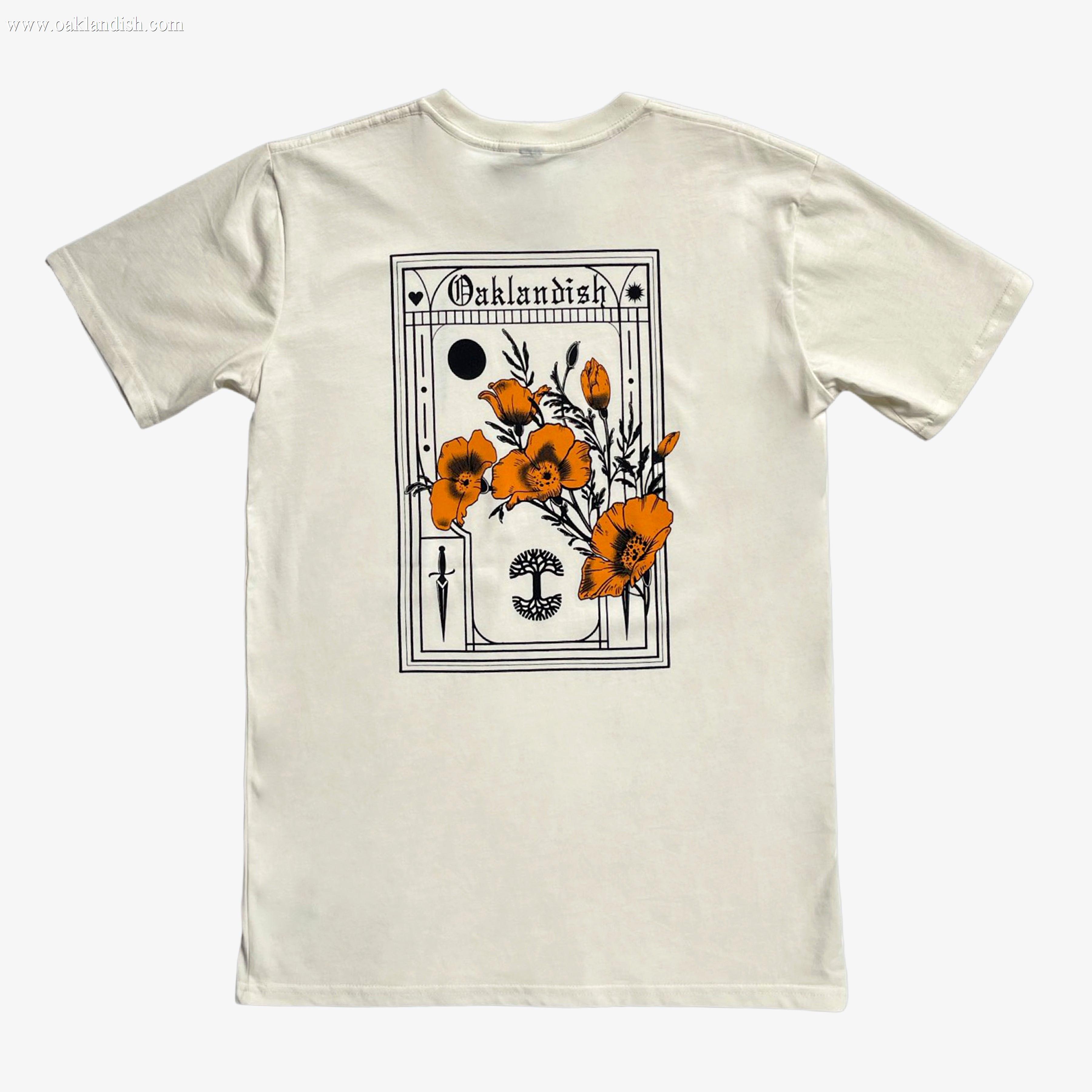 The Blossom Tee by Oaklandish is a classic fit, 100% cotton t-shirt featuring a rectangular graphic on the back. The design includes orange poppy flowers with black outlines, various geometric shapes, and the word "Oaklandish" at the top. This cream-colored shirt has a plain background and short sleeves.