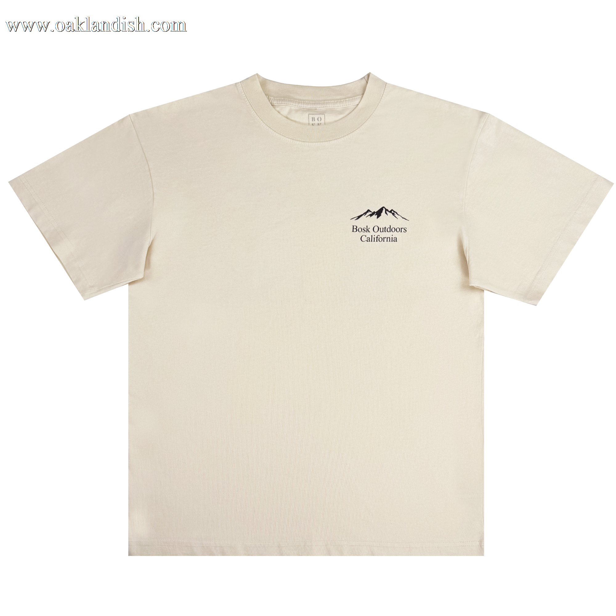 The Bosk Outdoors Tee from BOSK is a beige, heavyweight cotton T-shirt with an oversized fit. It features short sleeves, a round neckline, and a small black logo on the left chest with mountain outlines and "Book Outdoors California,” designed for men with a soft, casual style.