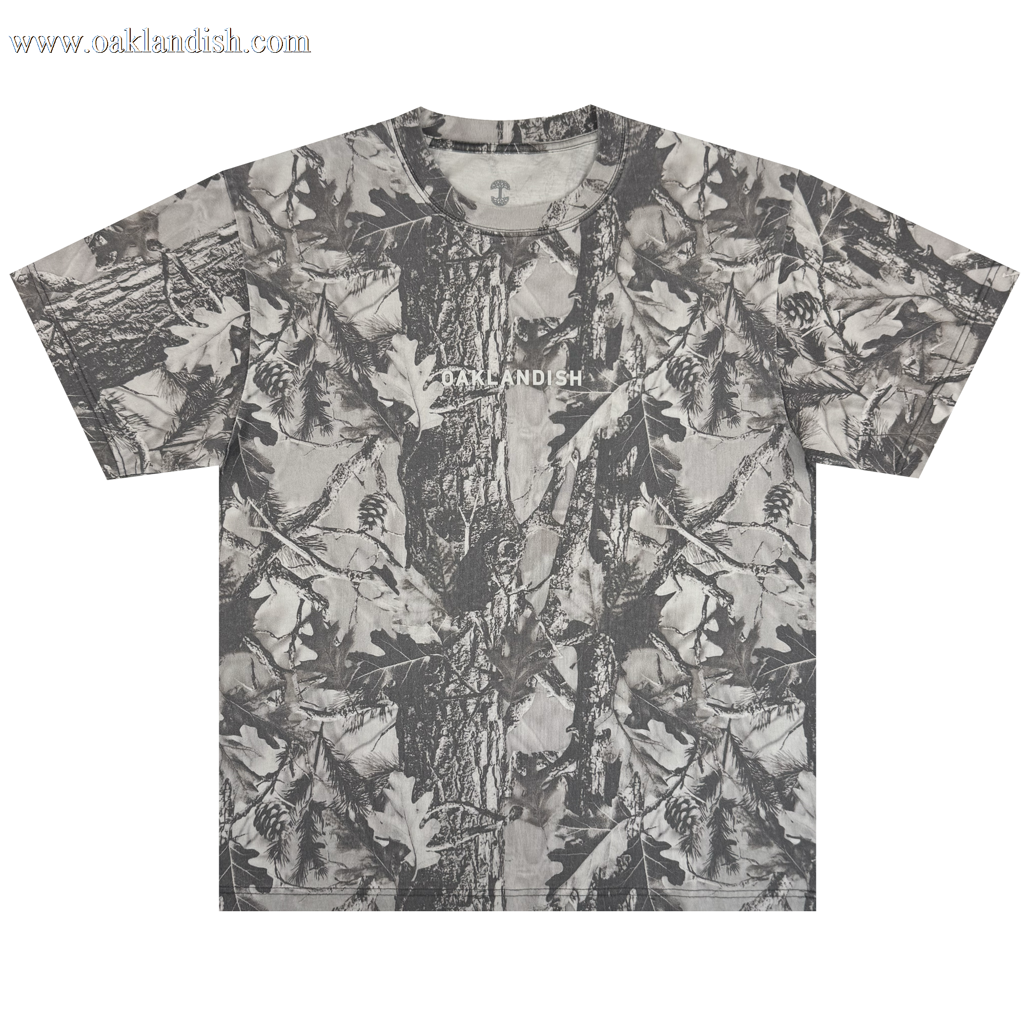 The Oaklandish Classic Logo Tee by Oaklandish is a heavyweight, short-sleeve oversized t-shirt in grey forest camo with tree bark, oak leaves, and pinecones. "OAKLANDISH" is printed in white across the chest. Shirt shown flat on a white background.