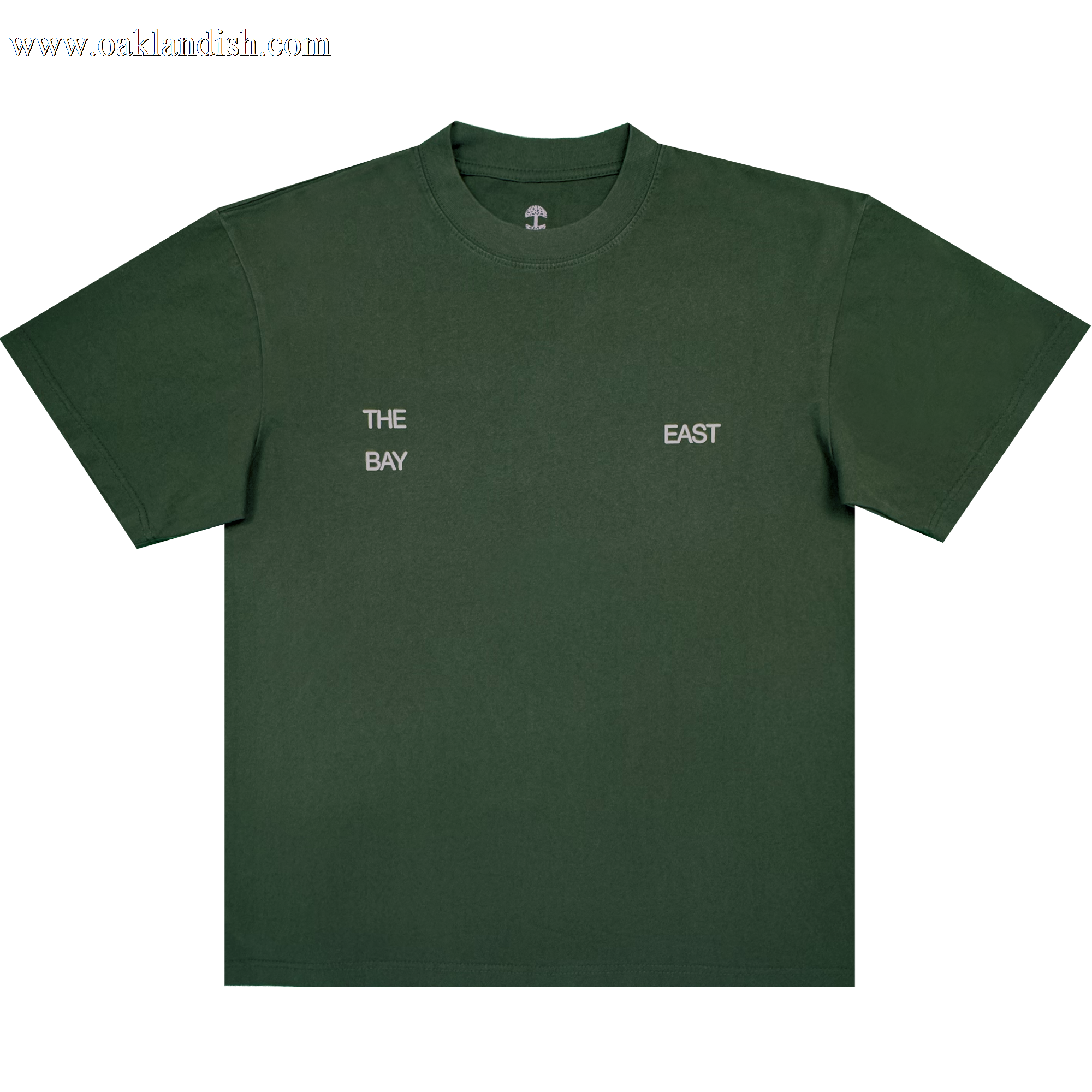 The East Bay Tee by Oaklandish is a dark green short-sleeve T-shirt from the Oaklandish x Toro y Moi collaboration, featuring small white text on the chest that reads "THE BAY" on the left and "EAST" on the right, separated by space. Inspired by Chaz Bear's unique style, this shirt is shown laid flat against a white background.