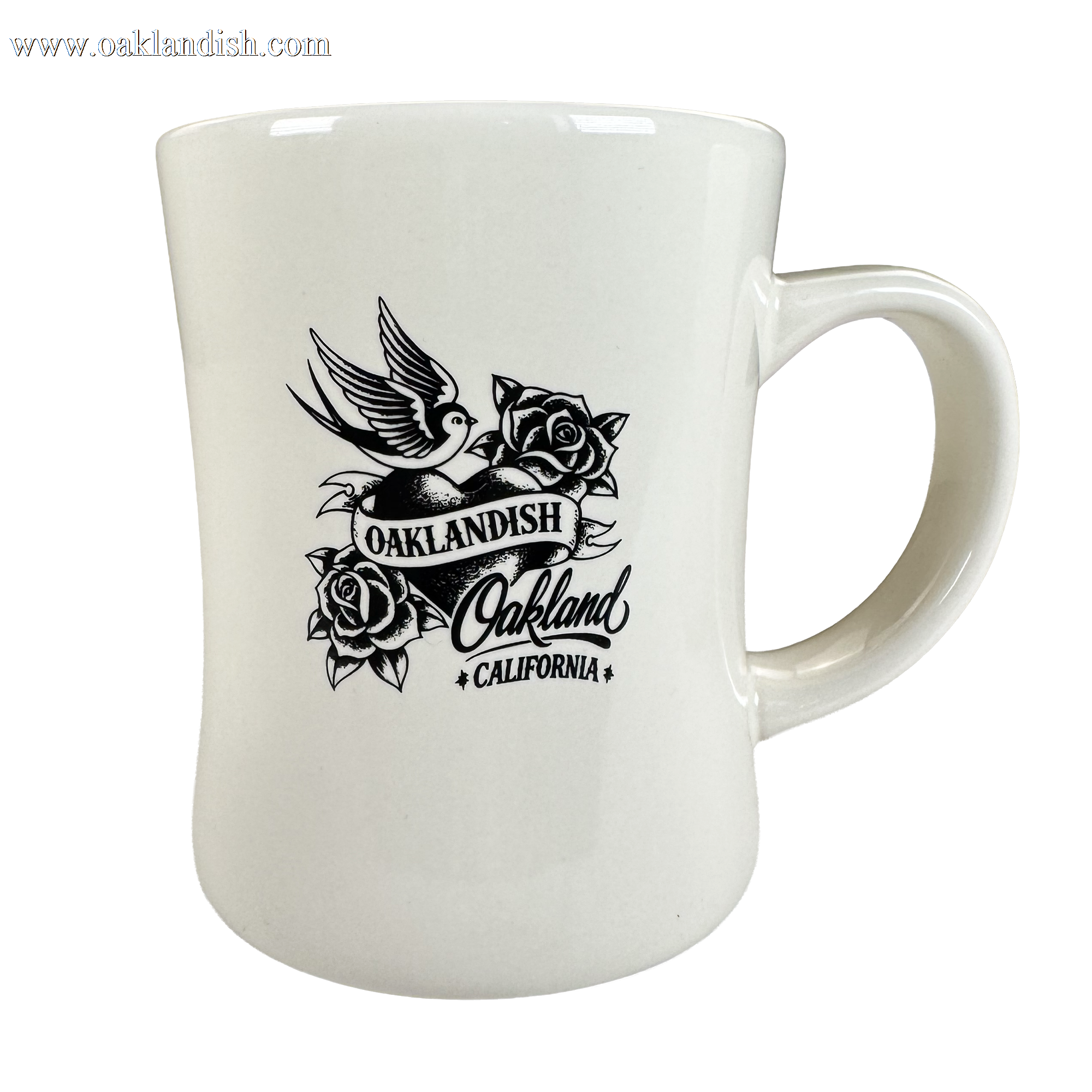 The Heart Diner Mug by Oaklandish is a white 14 oz ceramic mug with black flying bird artwork above an “OAKLANDISH Oakland CALIFORNIA” banner, framed by roses. It features a curved body and large handle for comfortable use.