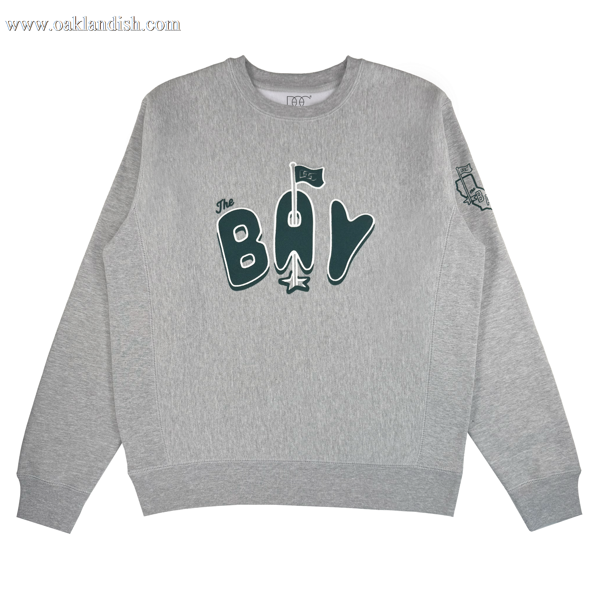 The Bay Flag Crew By DOC from Oaklandish is a heather gray heavyweight crewneck with "The Bay" in dark green, a stylized flag above the “A,” and a small embroidered sleeve graphic. Background is plain white.