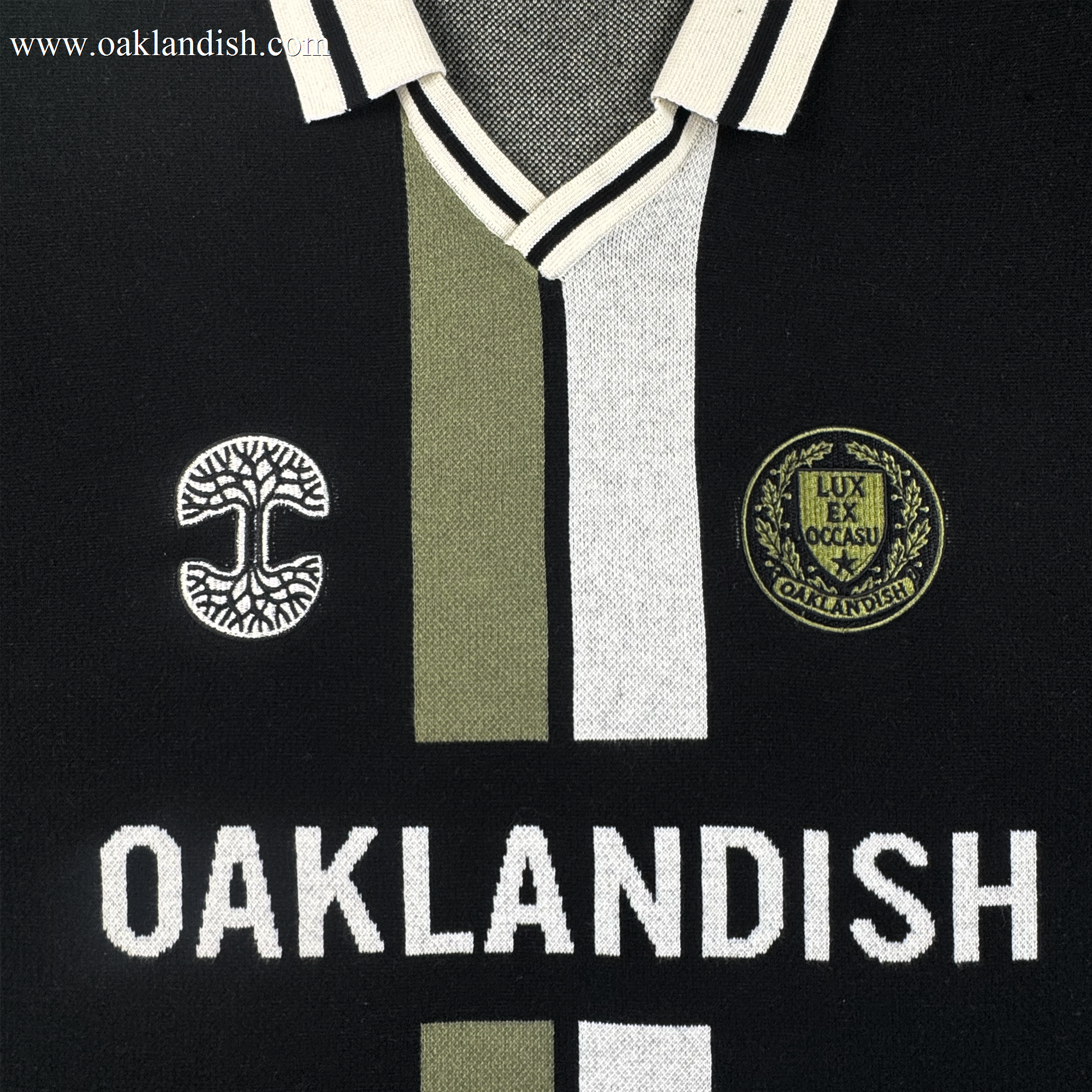 The Oaklandish Ease Jersey is a unisex black knit-collar top with white and olive-green stripes, two embroidered patches, and bold "OAKLANDISH" lettering across the chest.