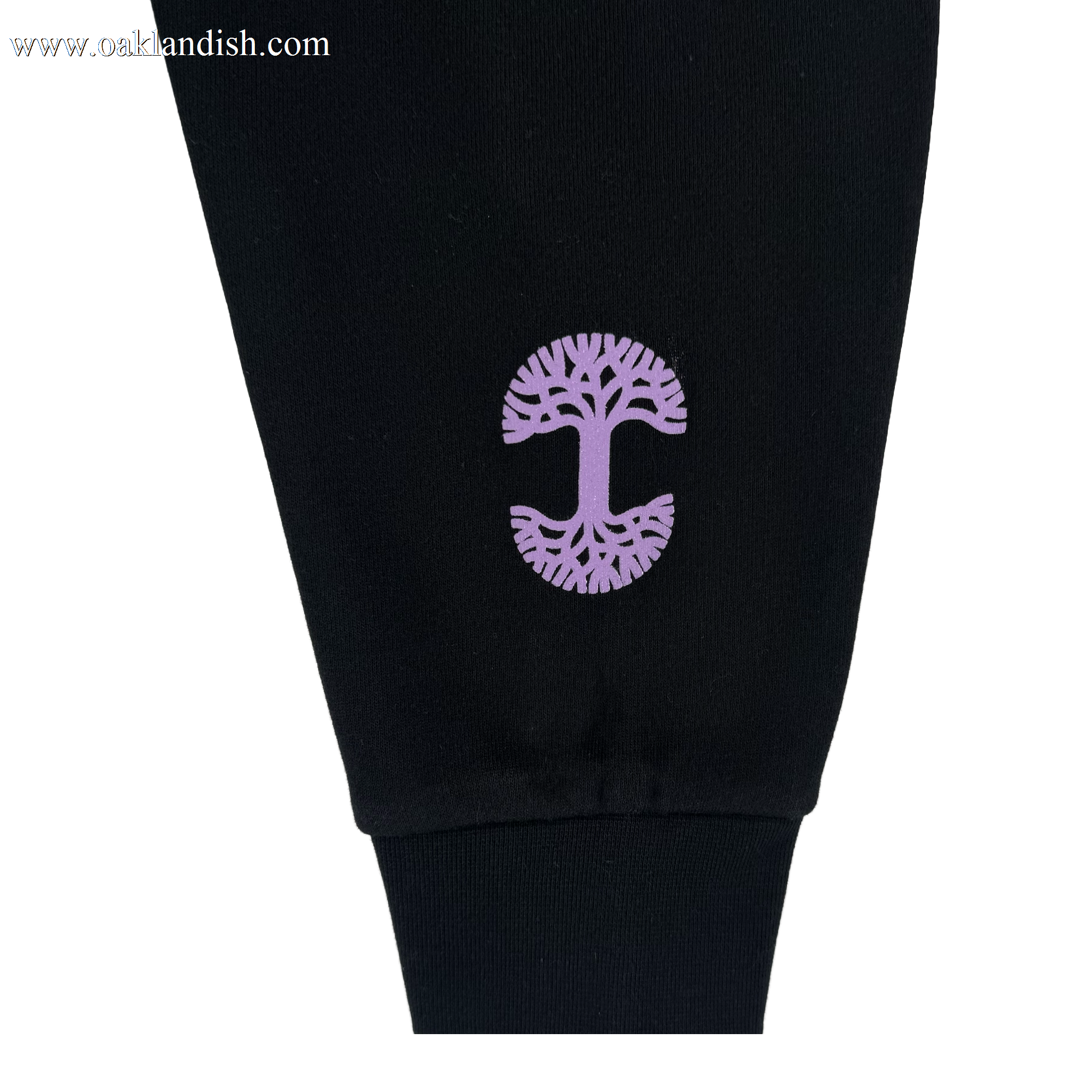 A close-up of a black pant leg shows a purple tree graphic with intricate branches and roots near the cuff. Pair it perfectly with the GSV Renowned Hoodie by GSV. The photo has a plain white background.
