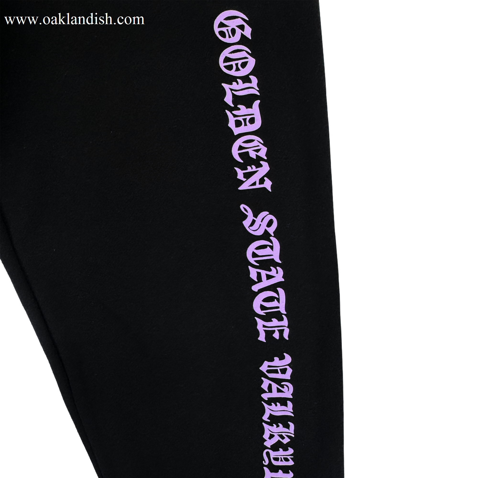 The GSV ROTV Pant by GSV features black fabric, men's sizing, and "GOLDEN STATE VALLEY" printed vertically in bold lilac Old English-style lettering, inspired by the Golden State Valkyries, on a plain white background.