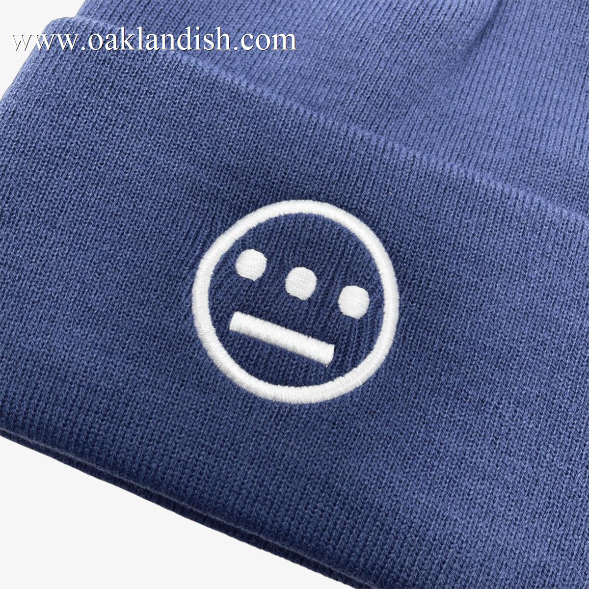 Close-up of white embroidered Hieroglyphics hip hop logo on front cuff of a navy cuffed beanie.