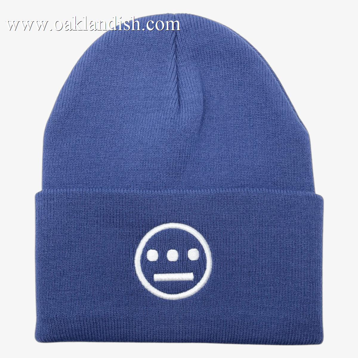 Introducing the Hiero Classic Cuff Beanie by Hieroglyphics: a blue knit beanie with a folded brim, featuring an embroidered white logo on the front. The logo, reminiscent of hieroglyphics, depicts a minimalist face with two horizontal lines for eyes, a single line for a mouth, and three vertical dots above the eyes in a symmetrical design.