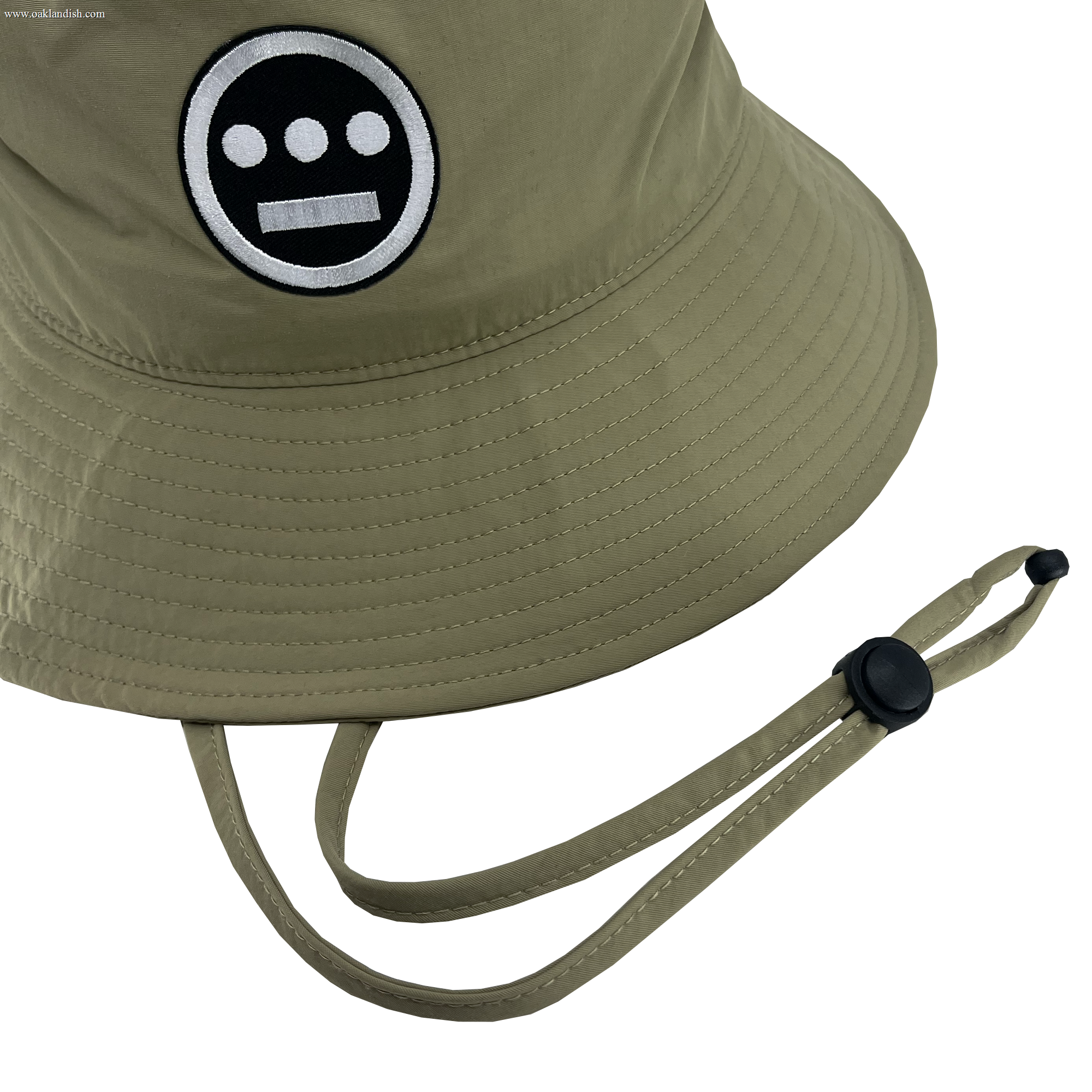 Detailed view of wide brim Khaki bucket hat with toggles and Hiero logo patch .