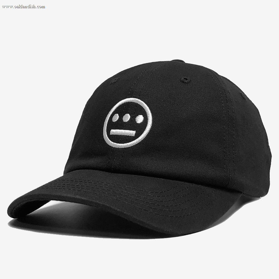 The Hiero Logo Dad Hat by Hieroglyphics is a black dad hat with a curved brim, featuring a white embroidered logo on the front. The logo consists of a circle with a horizontal line through the middle and three dots above, resembling stylized hieroglyphics against a plain, white background.