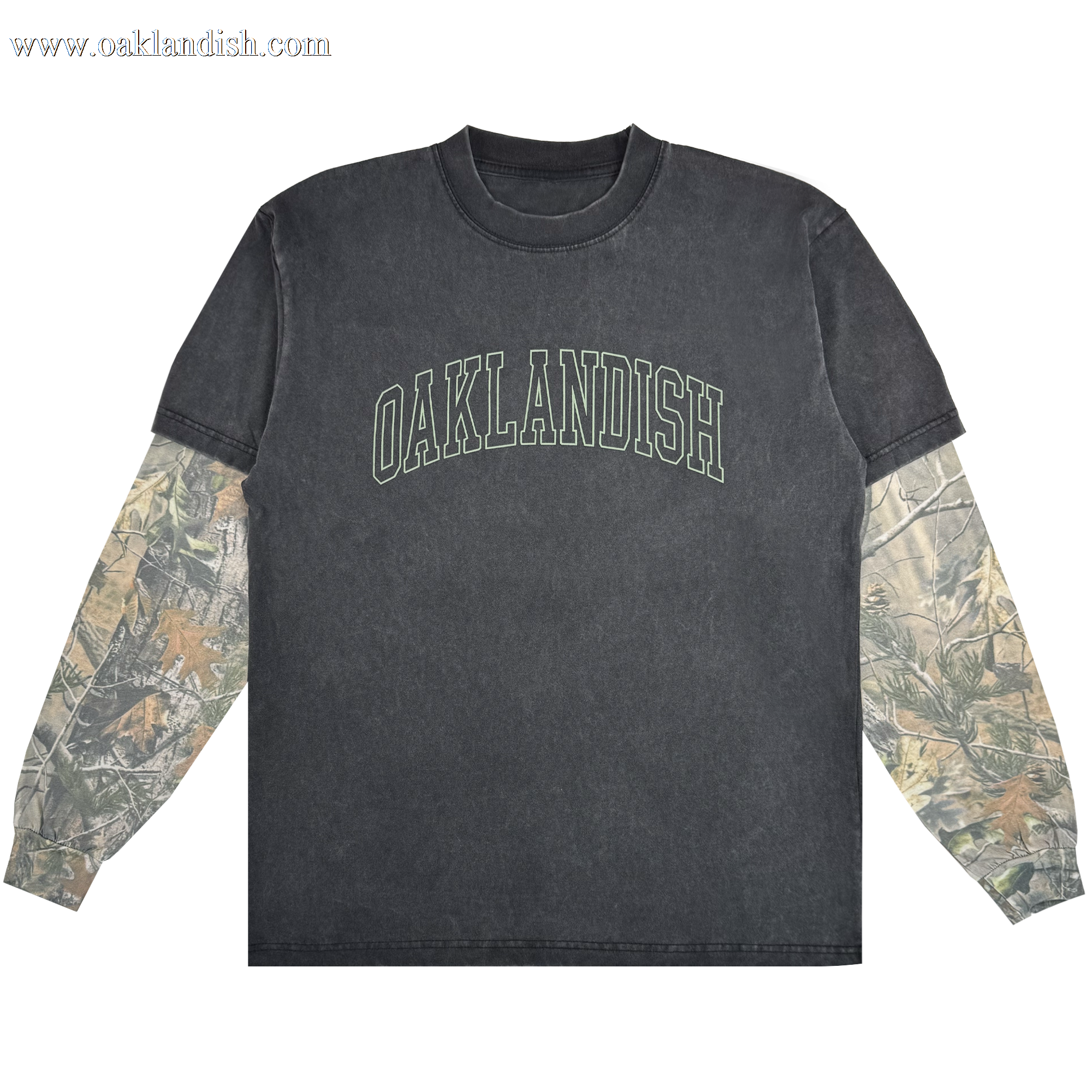 The Oaklandish Hunter LS Tee is a black washed crewneck with bold, arched green "OAKLANDISH" text and camo sleeves under short sleeves. Made from 100% cotton, this standout shirt is shown against a white background.
