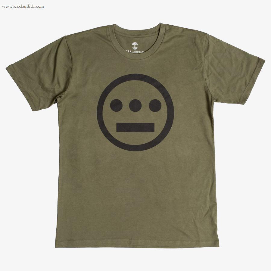 The Hiero Classic Logo Tee by Hieroglyphics is an olive green, classic fit T-shirt made from 100% cotton. It features a black logo centered on the chest, which is a simple geometric design resembling hieroglyphics. The logo consists of a circle with three dots forming a horizontal line and a straight line beneath them. The shirt has a crew neckline.