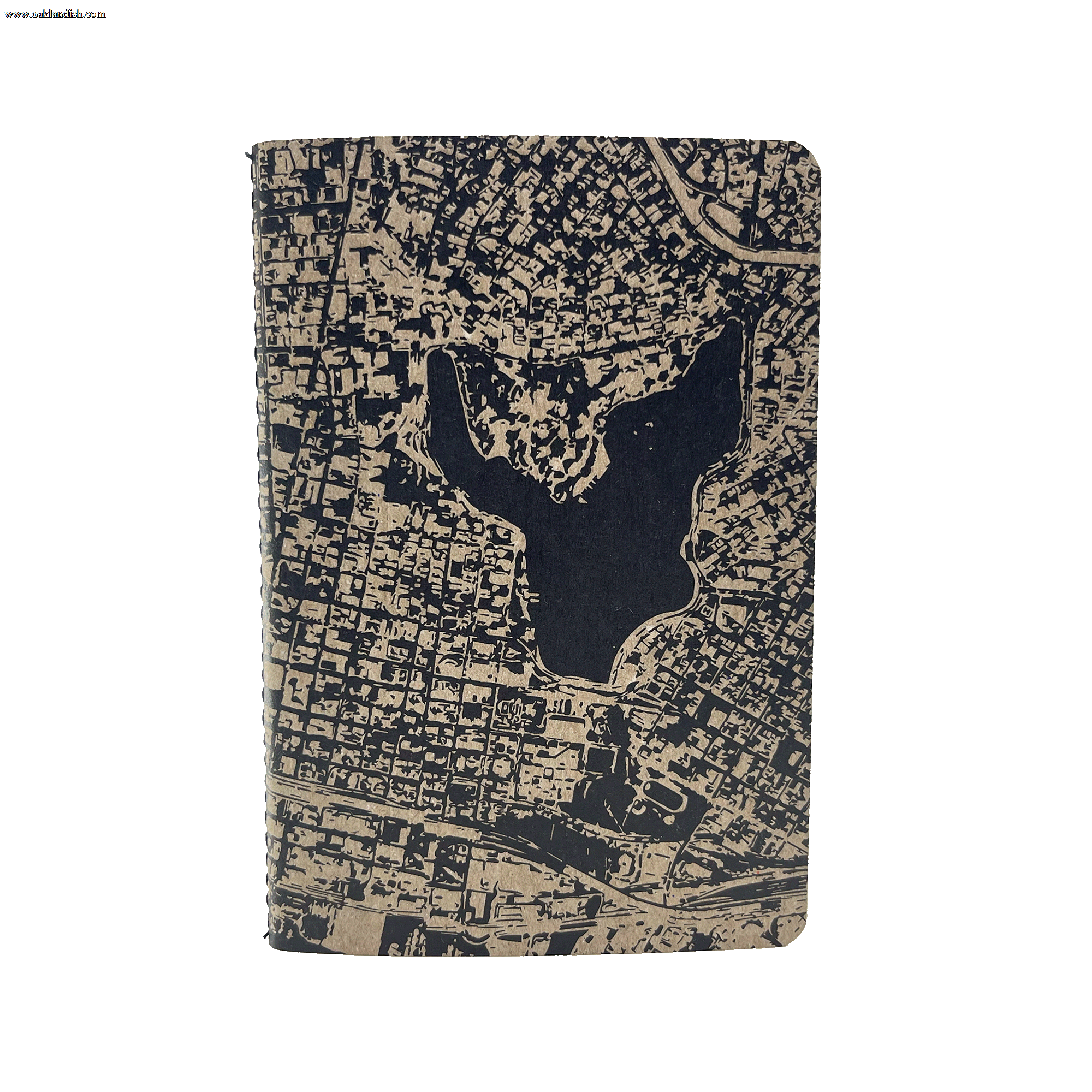 The Aerial Map Mini Notebook by Never Elsewhere features a textured, tan letterpress cover with an intricate black map design. The map showcases a cityscape that includes a central body of water surrounded by a grid-like pattern of streets and blocks. Inside, the dot grid paper perfectly complements the detailed exterior.