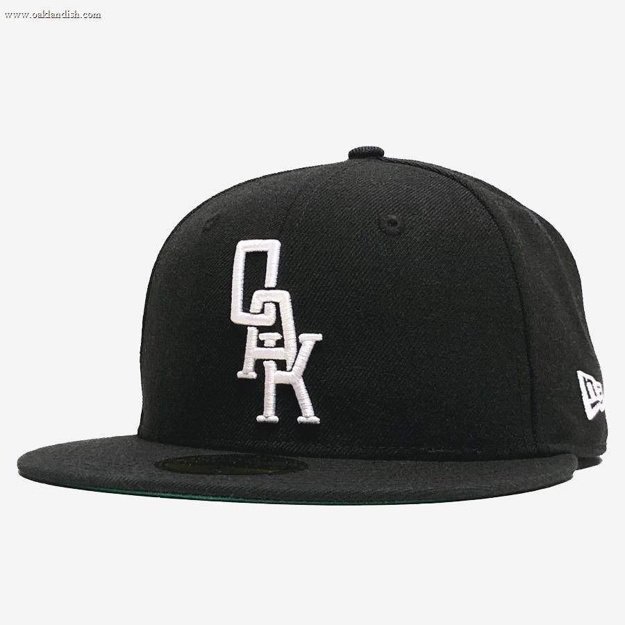 The New Era OAK 59FIFTY Fitted Cap by Oaklandish is a sleek, modern hat with a black fitted design and a flat brim, featuring the OAK logo embroidered in white stacked letters on the front. The side of the cap showcases the New Era logo in white.