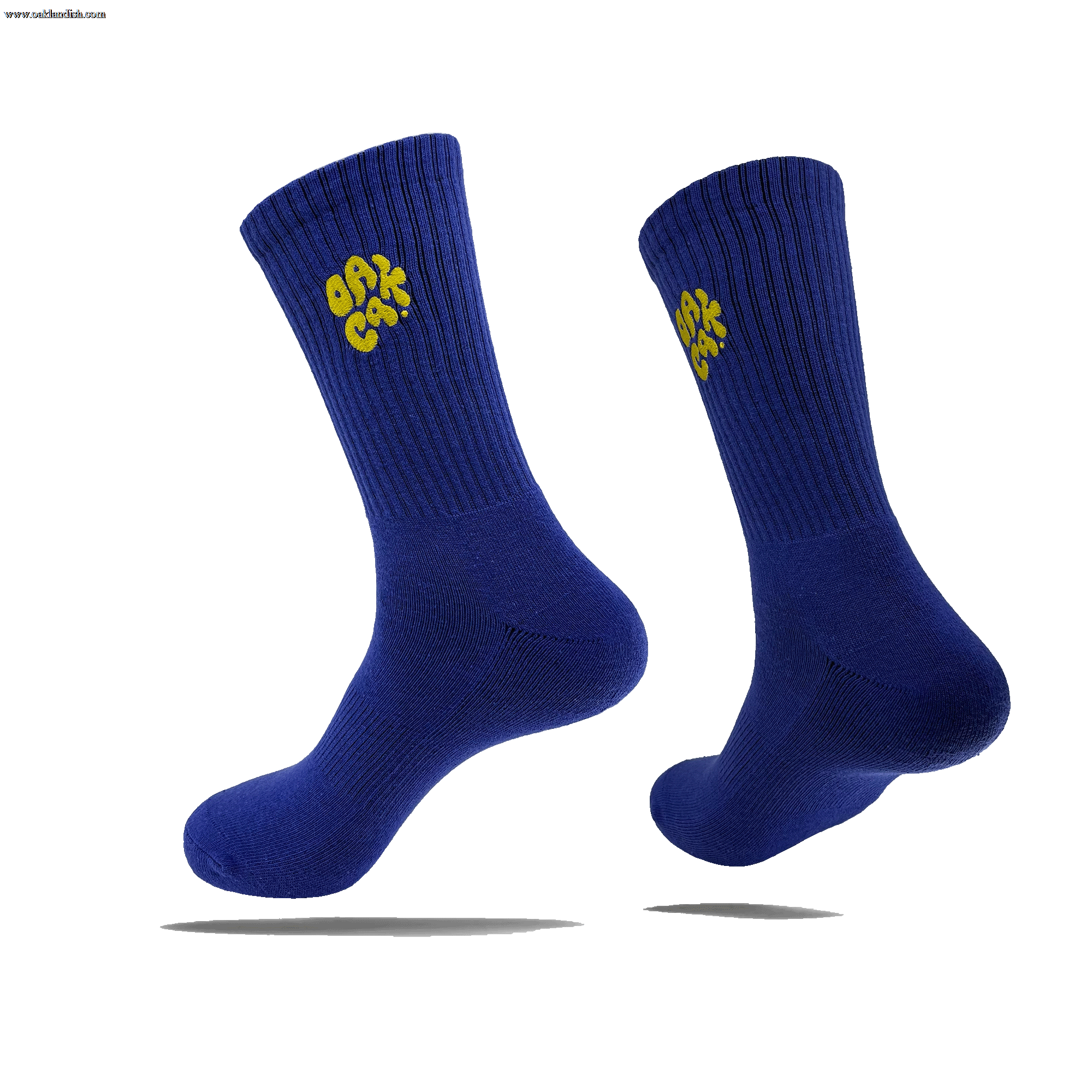 Side view of a pair of blue crew socks with a yellow embroidered OAK CA blob-style wordmark on the side calves.