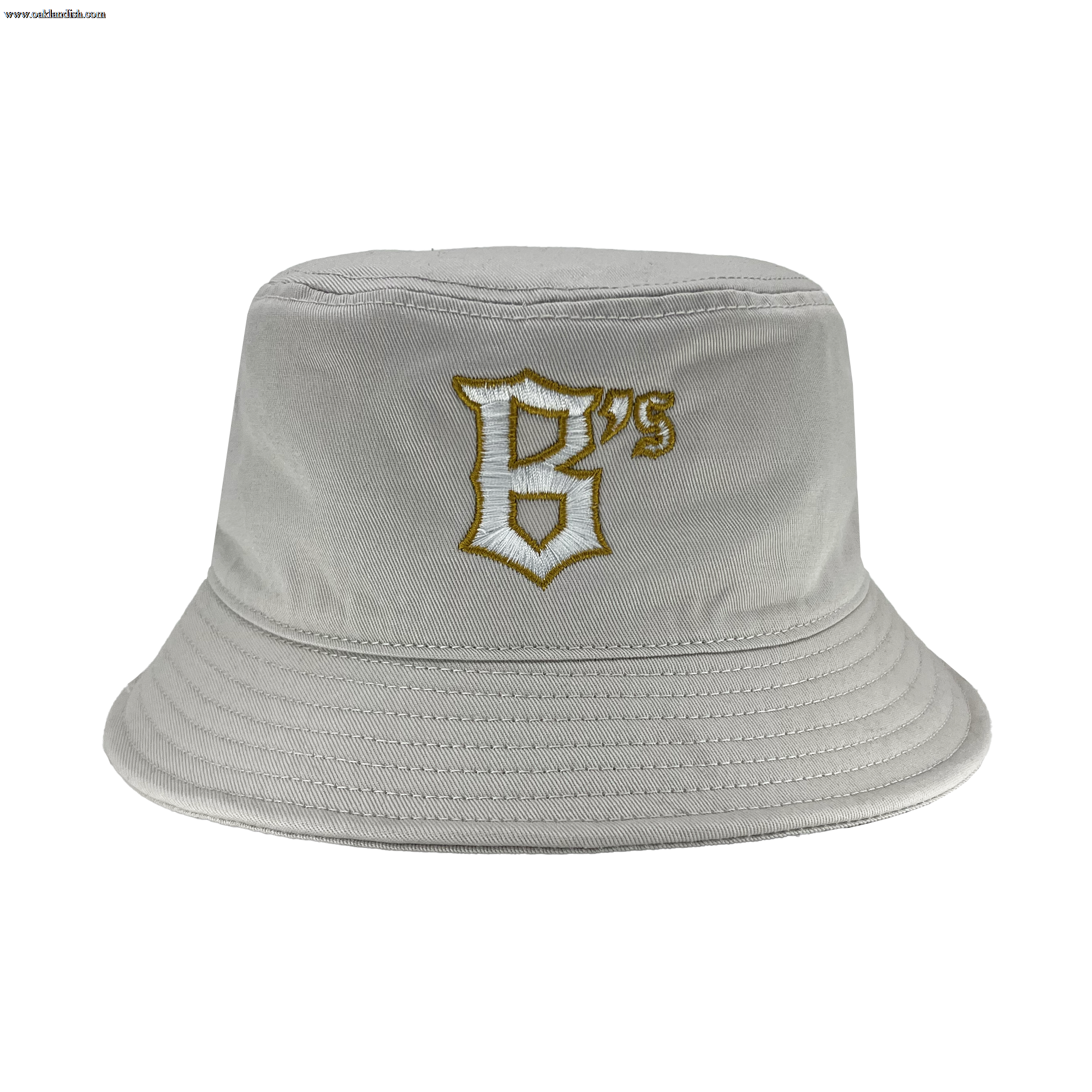 The Oakland Ballers B Bucket Hat is displayed in light grey with a wide, downward-sloping brim. The front showcases an embroidered design: a stylized letter "B" in white with a golden outline and the number "75" in gold, reflecting the legacy of the Oakland Ballers and their storied West Coast franchise history. The hat seems to be crafted from soft, flexible fabric.