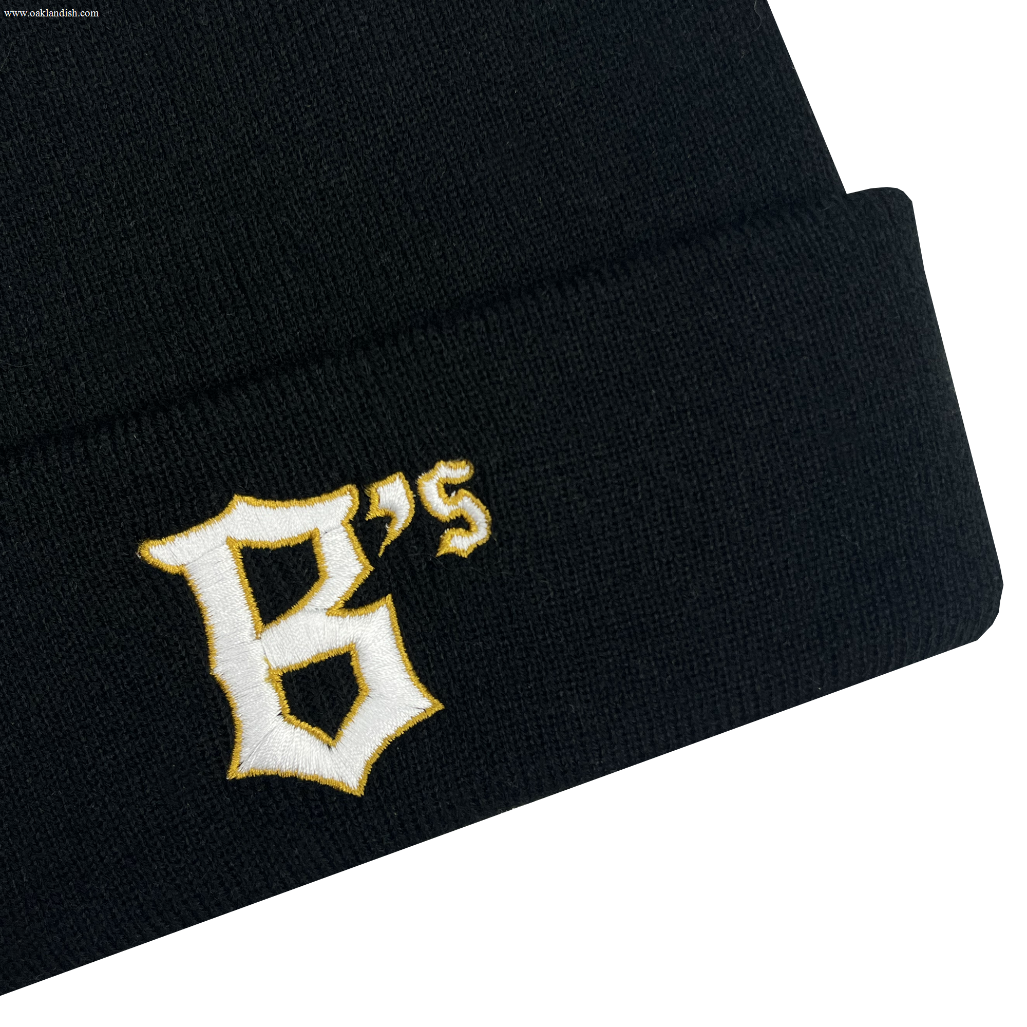 The Oakland Ballers Logo Beanie, a black knit beanie, features the embroidered letters "B's" in a stylized yellow and white font on the cuff, reminiscent of a professional baseball team logo. The plain white background highlights the beanie.