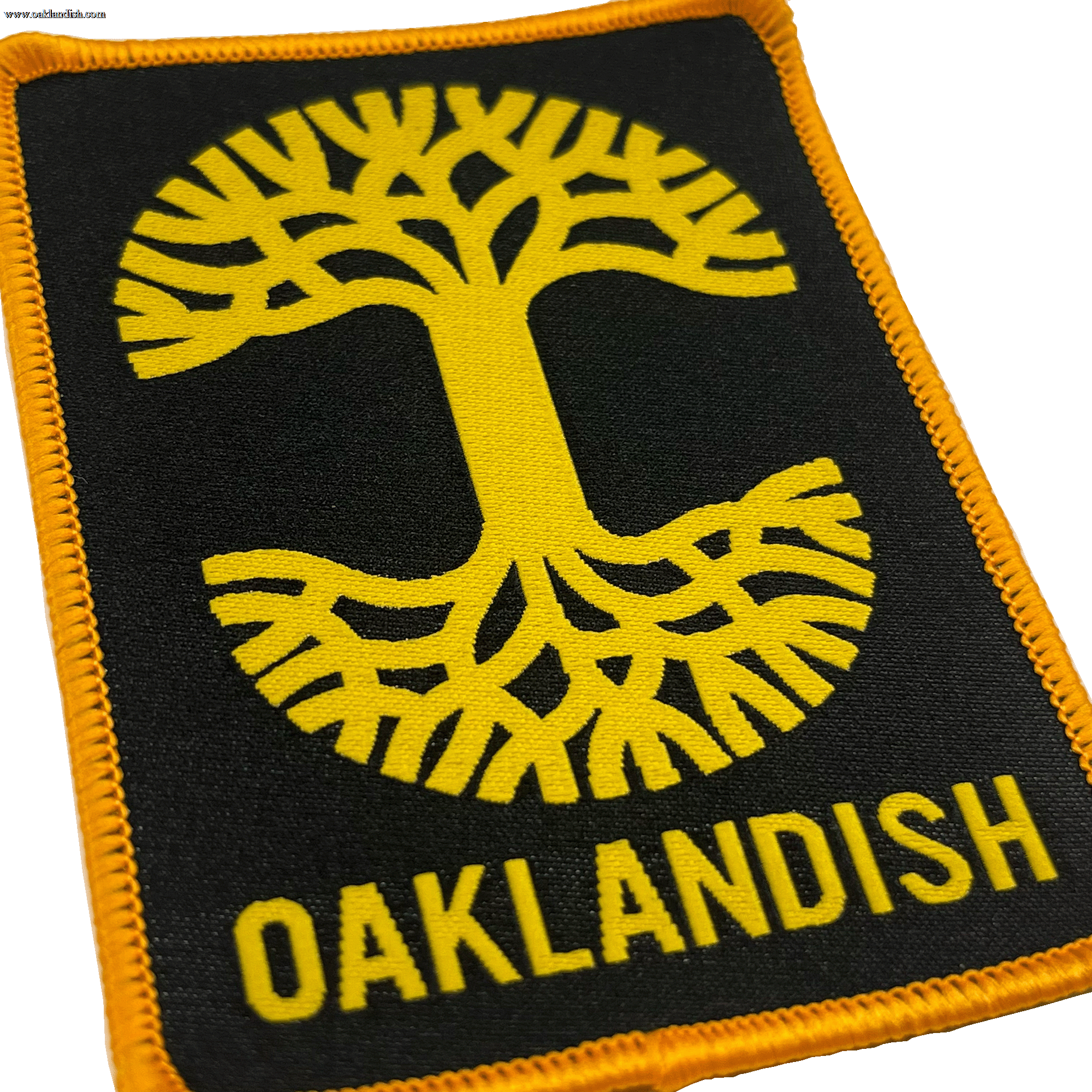 Close-up of black woven iron-on patch with gold Oaklandish tree logo and wordmark.