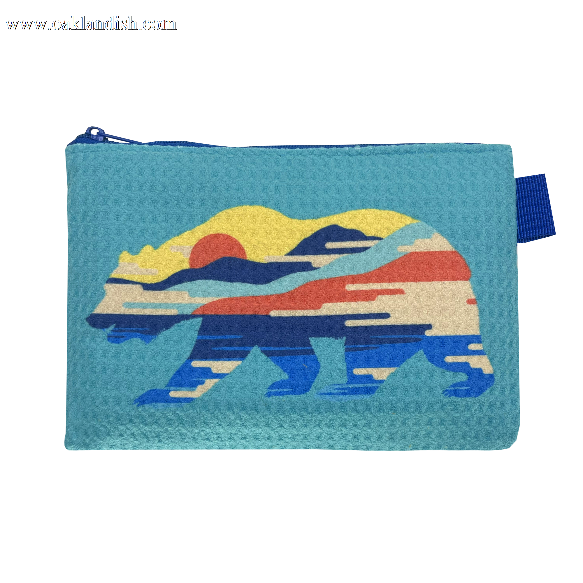 The Sunset Bear Pouch by Oaklandish is a small blue zip pouch with a top zipper, featuring a stylized California grizzly design. The bear is depicted in a colorful pattern showcasing elements of nature such as mountains, a sunset, and a forest, primarily using red, yellow, blue, and beige hues.