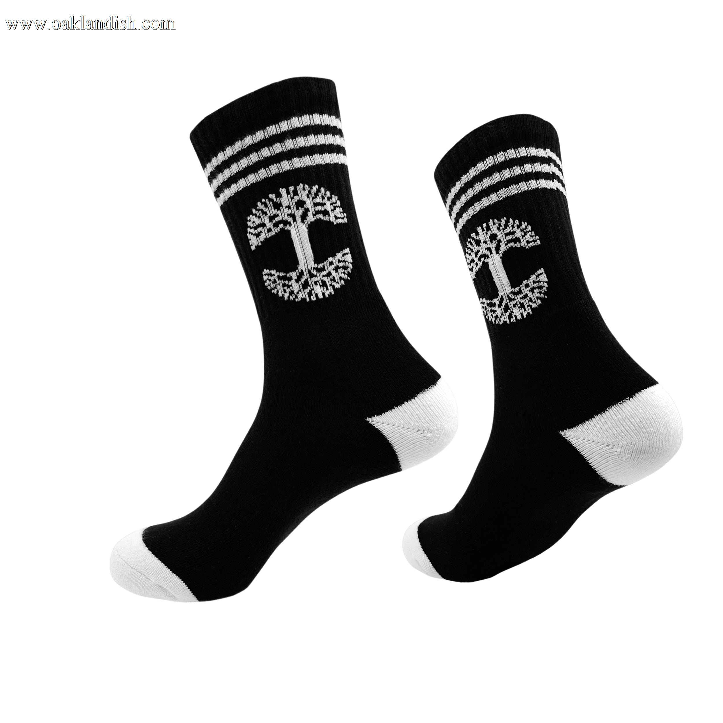 A pair of Retro Classic Socks from Oaklandish, exceptionally comfy in black, featuring a white tree emblem and two horizontal white stripes near the top. The socks have unique white heels and toes, displayed with one sock slightly in front of the other against a plain white background.