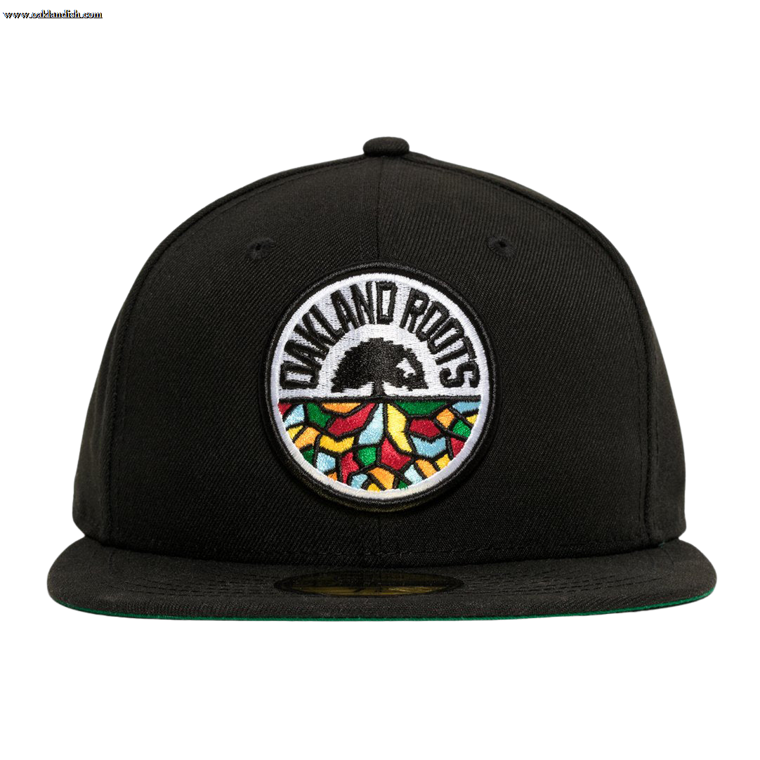 A New Era Oakland Roots SC 59FIFTY Fitted Cap in black, featuring a circular embroidered patch on the front. The patch showcases the words "Oakland Roots" at the top, a black tree in the center, and colorful geometric shapes resembling a mosaic at the bottom. This sports club cap comes with a flat brim and a green underside.