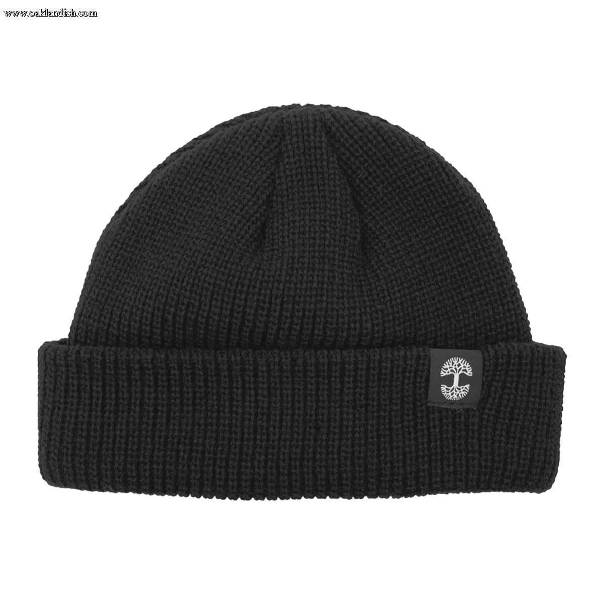The Ramos Beanie by Oaklandish is a black knit beanie featuring a folded cuff. The cuff showcases an embroidered logo of a white tree inside a gray circular border. Made from woven acrylic, the knit pattern's texture is clearly visible, contributing to its cozy and warm appearance.