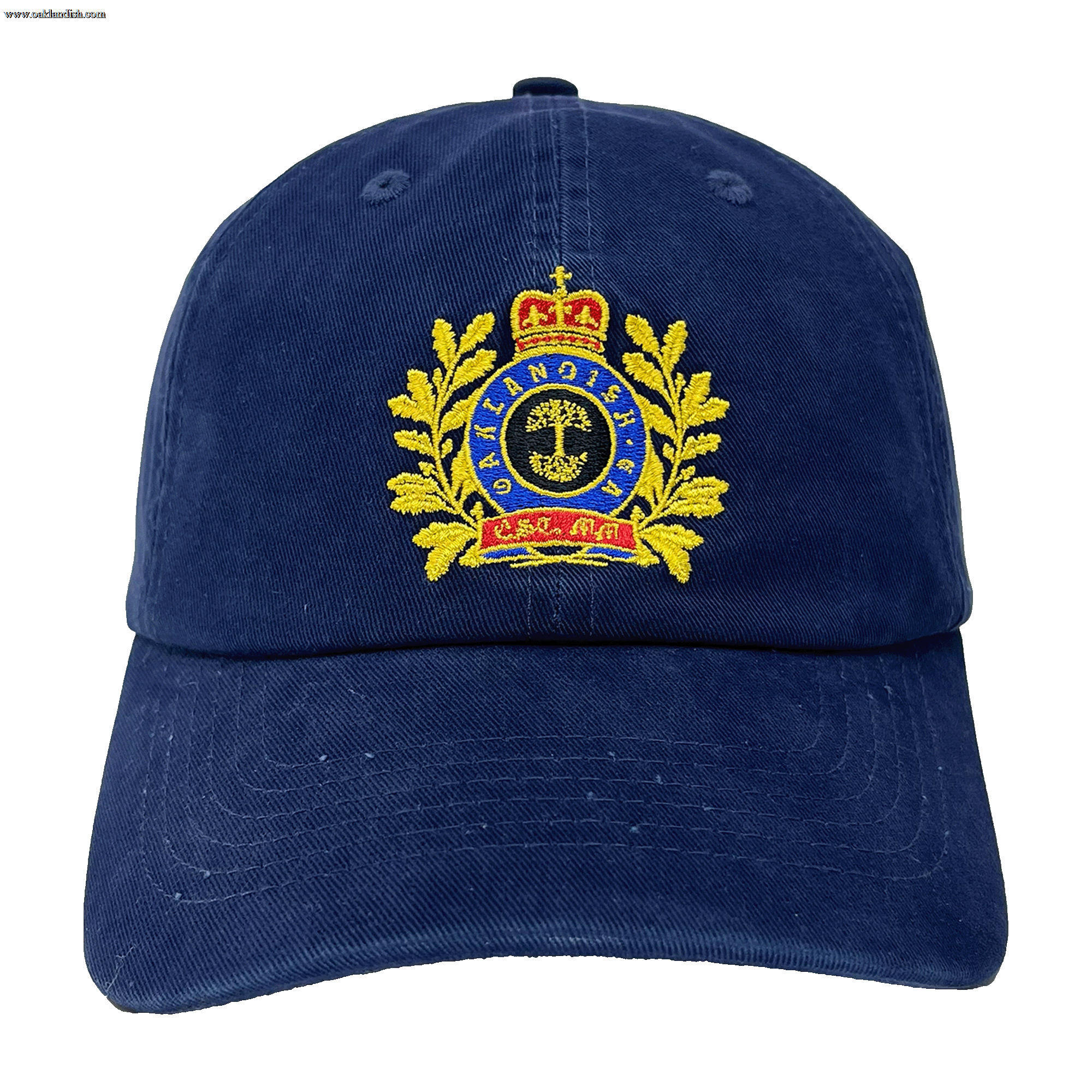The Regal Crest Dad Hat by Oaklandish is a navy blue hat featuring an embroidered gold emblem on the front. The intricate design includes a crown at the top, gold laurel wreaths on either side, and a central shield with detailed symbols. Blue text is threaded within the emblem, framed by the wreaths. Made from 100% cotton, it also includes an adjustable strap for added comfort.