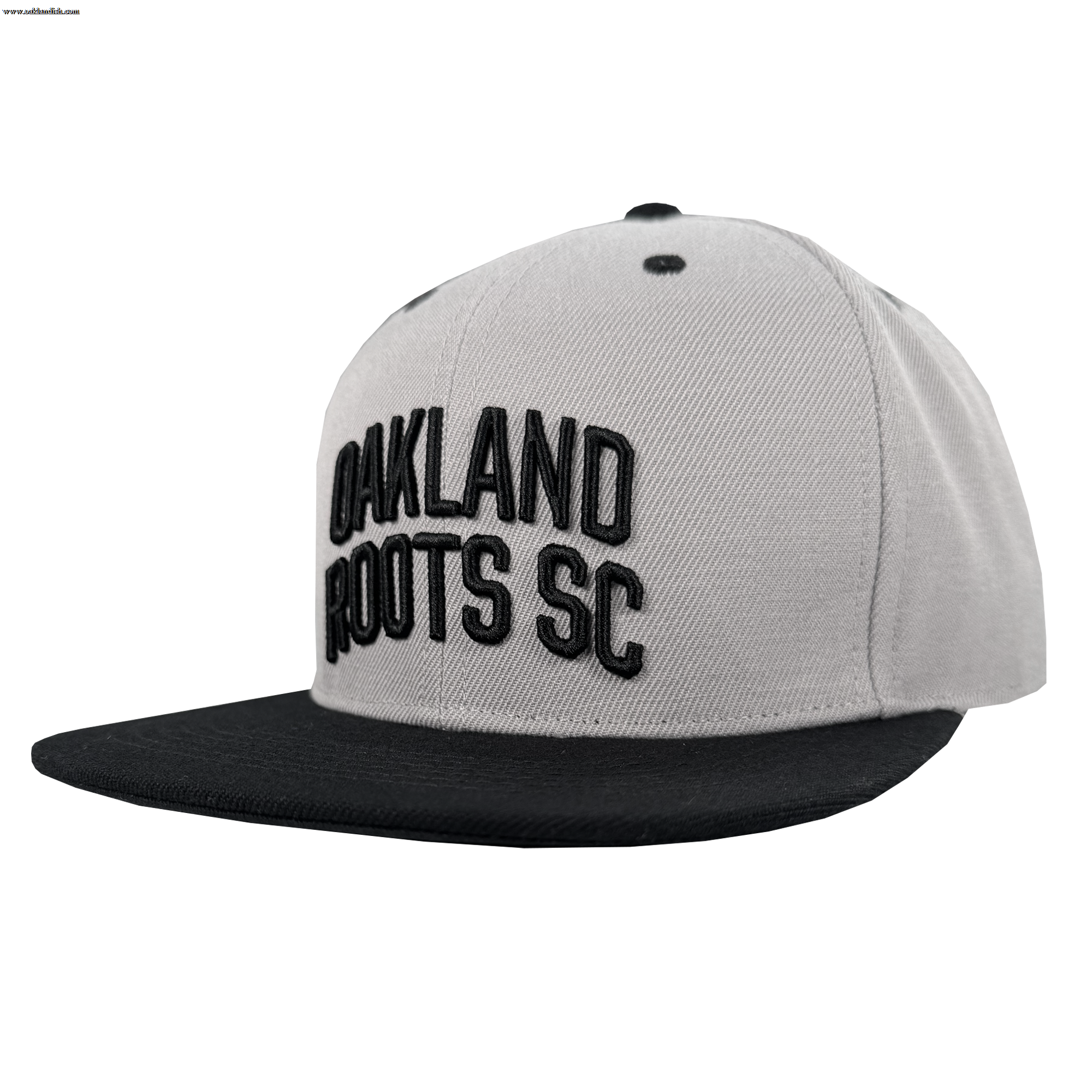 The Oakland Roots SC Arch Text Snapback by Oakland Roots SC is a light gray cap with a flat black brim and bold, raised black "OAKLAND ROOTS SC" text on the front panel, shown at a left angle against a white background.