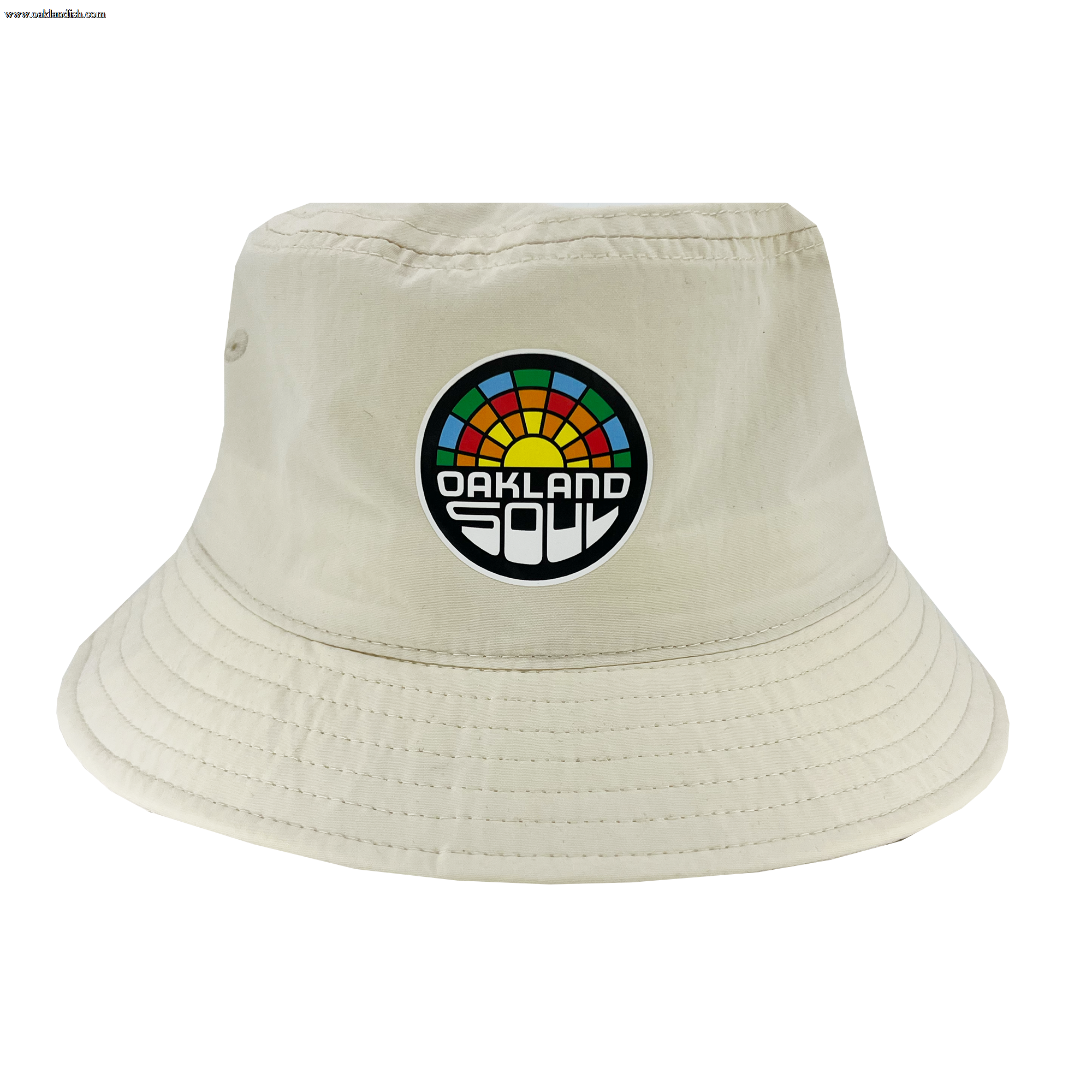 The Oakland Soul Logo Bucket Hat, a beige hat adorned with the "Oakland Soul" logo on the front, celebrates our local women's soccer team in the USL W-League. The logo features a vibrant, semi-circular sunset design with "Oakland Soul" prominently displayed in bold black and white letters below it. Visible stitching around the brim adds to its detail.
