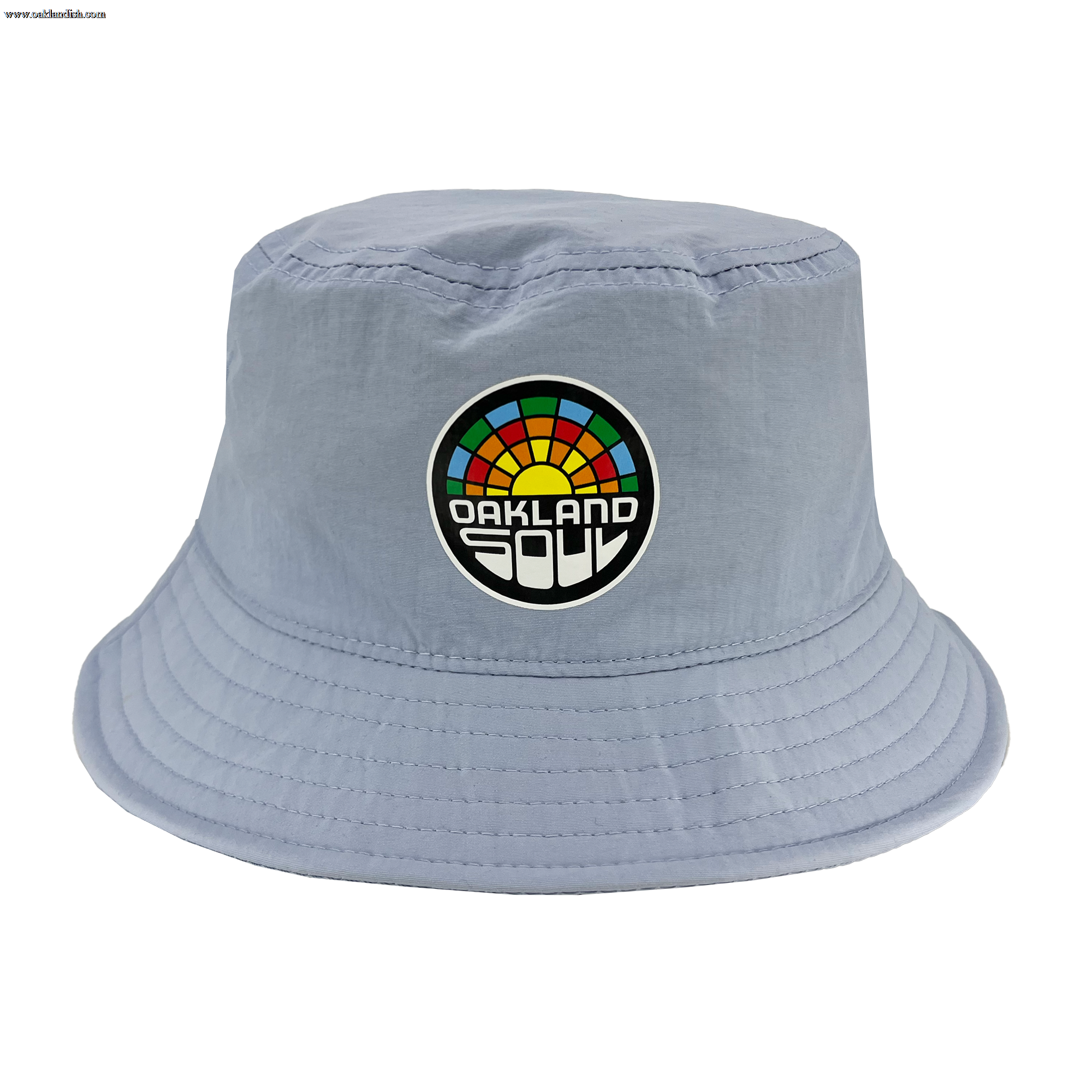 The Oakland Soul Logo Bucket Hat by Oakland Soul is a light blue accessory adorned with a colorful rainbow patch and the words "Oakland Soul" in bold white and black font on the front. Inspired by Oakland's women's soccer team, this hat features a soft, unstructured brim with visible stitching around the edges.