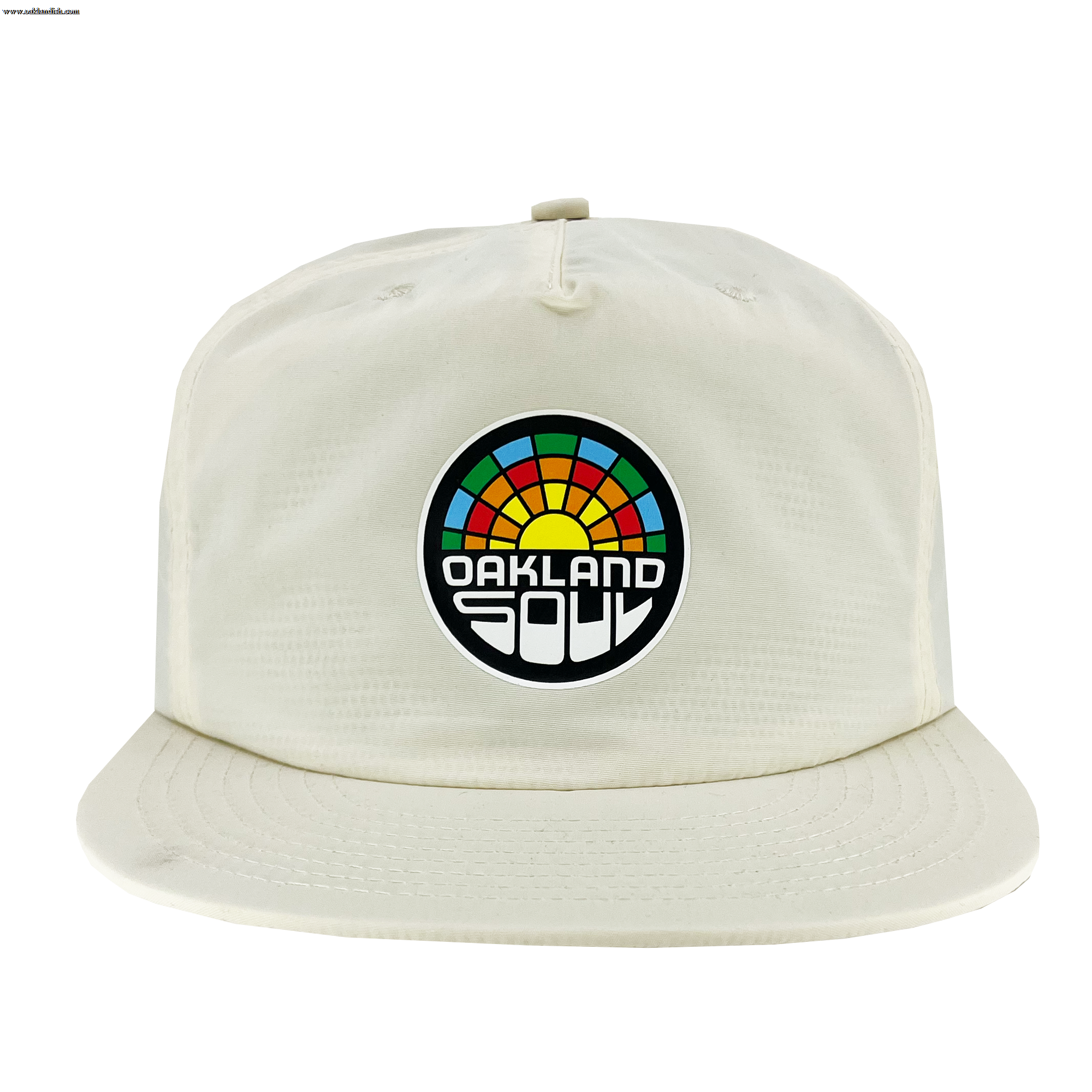 The Oakland Soul Surf Cap, a white baseball cap with a flat brim, showcases a circular logo on the front. The logo features a colorful, semi-circular design resembling a sunrise or rainbow with "OAKLAND SOUL" in bold white letters against a black background, celebrating Oakland Soul, our women's soccer team in the USL W-League.