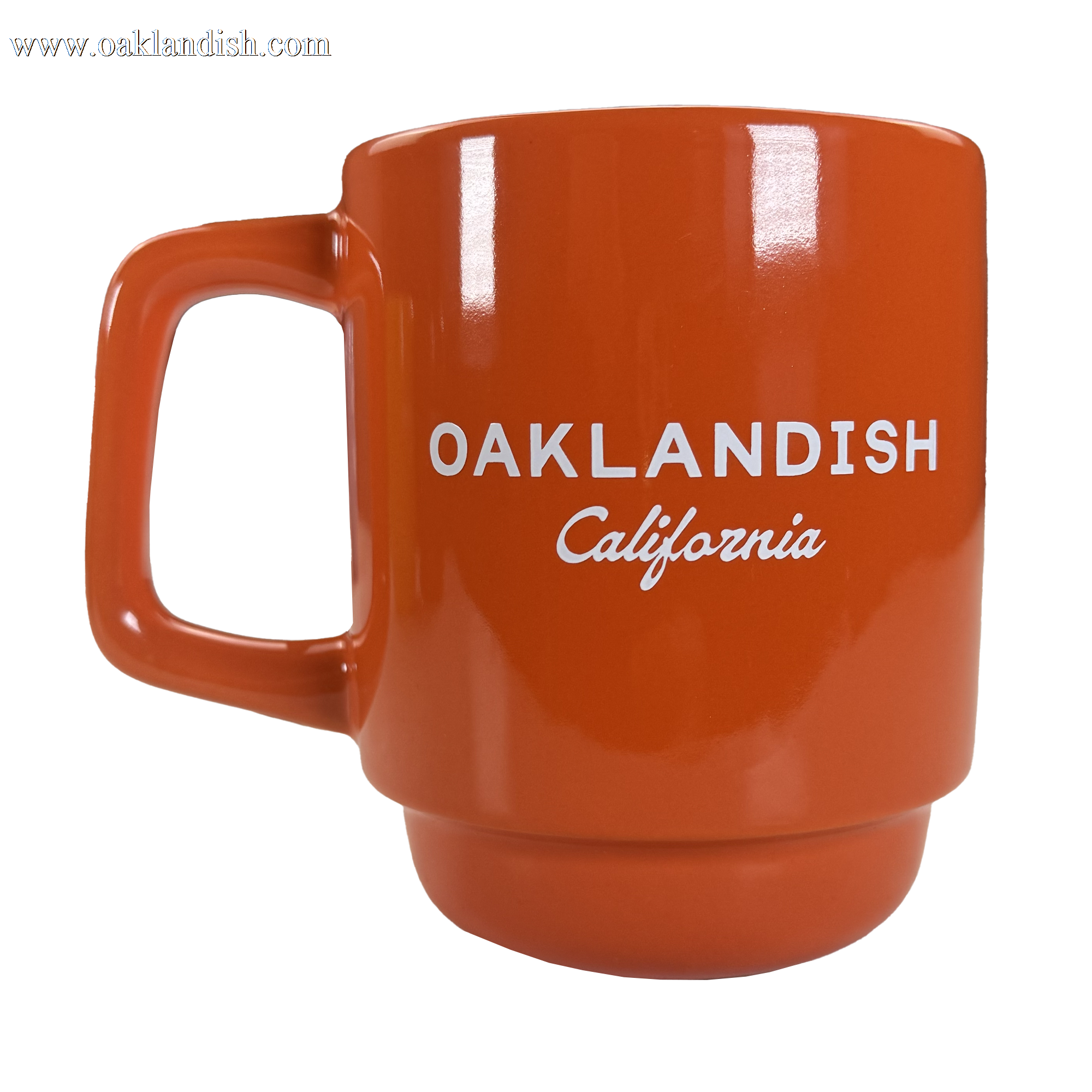 The Oaklandish Logo Stack Mug is an orange ceramic drinkware cup with a squared handle and "OAKLANDISH California" printed in white, shown on a white background. The design is minimal, with no extra decorations or graphics.