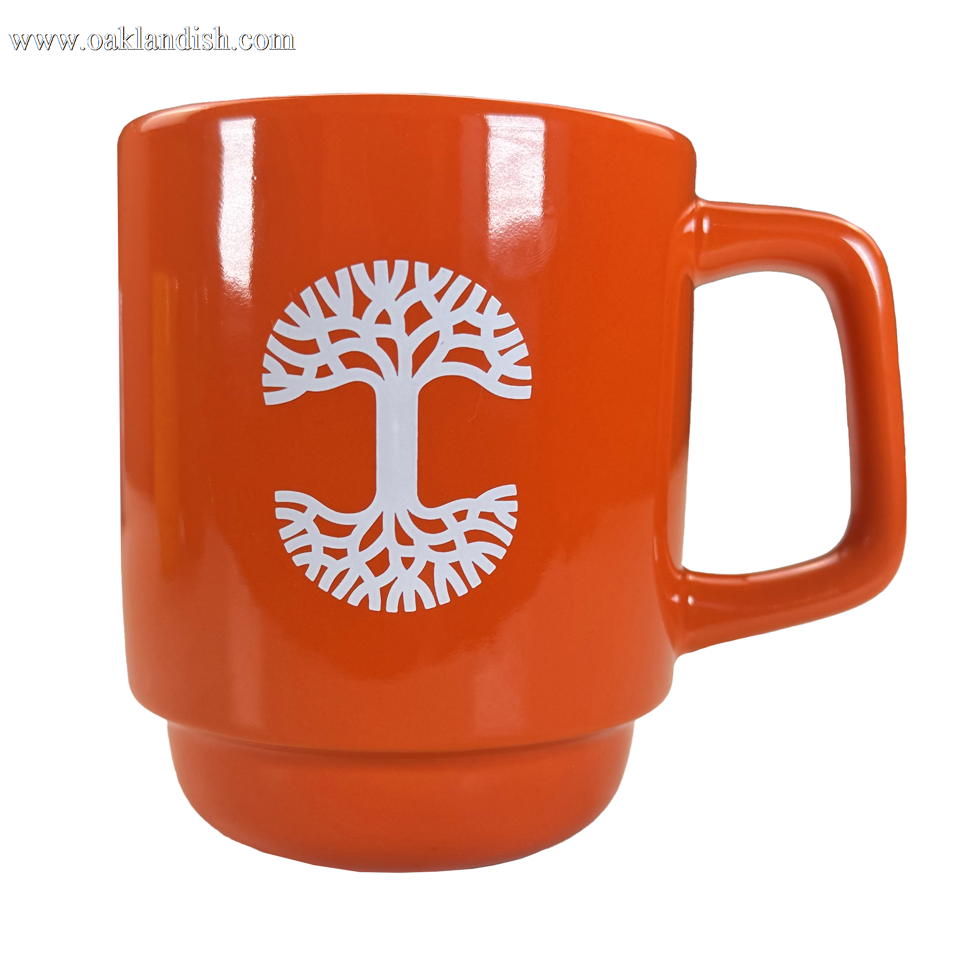 The Oaklandish Logo Stack Mug is an orange ceramic coffee cup with a large handle, featuring a white stylized tree with spreading roots and branches centered on the front. The background is plain white.