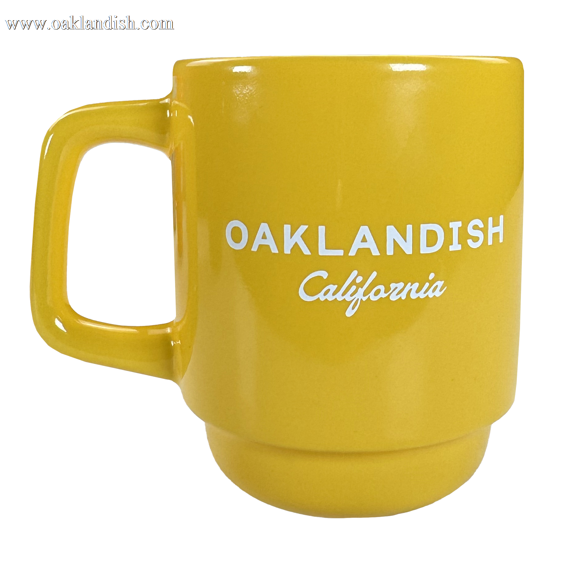 The Logo Stack Mug by Oaklandish is a bright yellow ceramic mug with a large handle. "OAKLANDISH" in bold white uppercase letters and "California" in small cursive are printed on the front. Background is plain white.